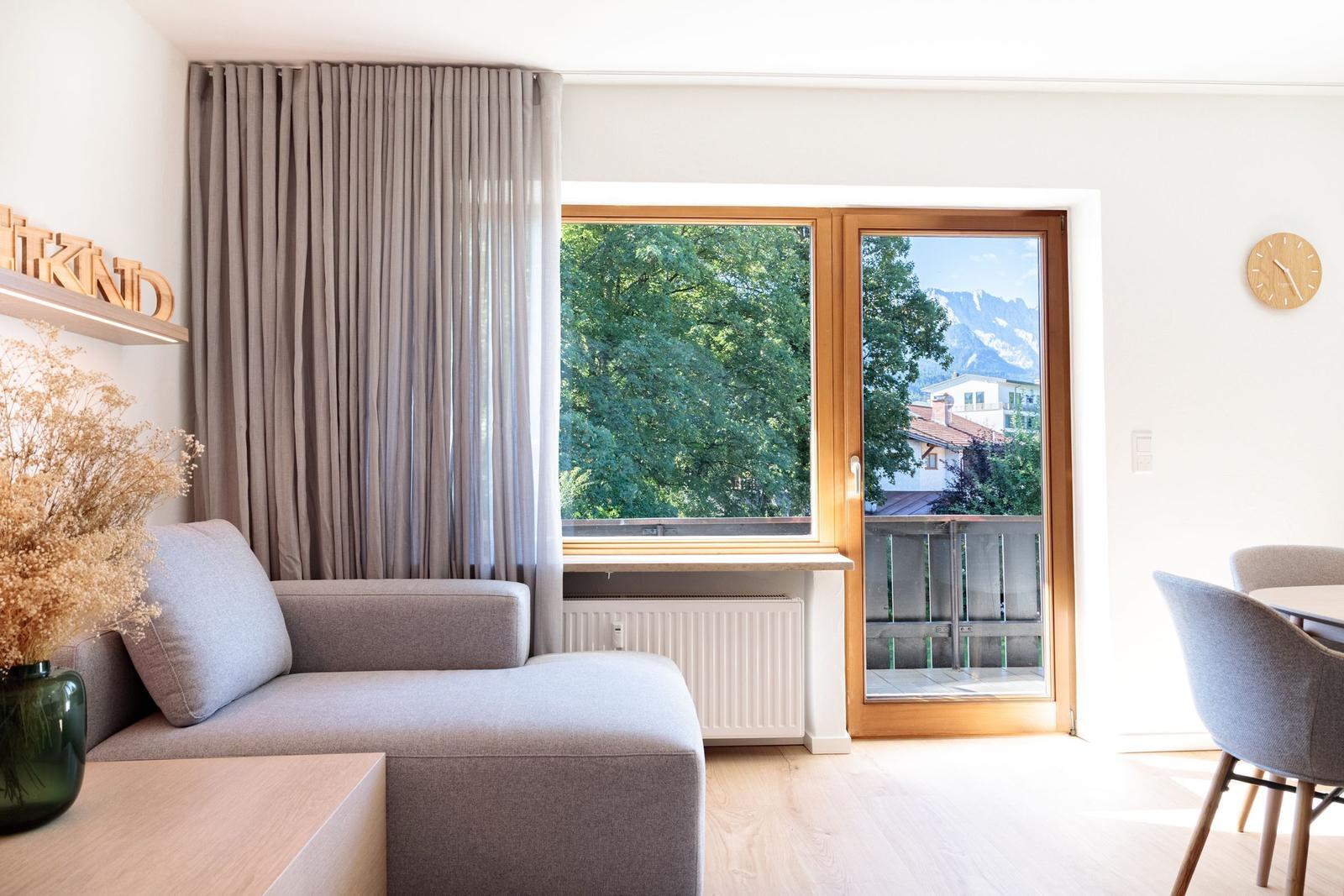 Wohnzimmer mit Sofa, Blick auf Balkon und Berge