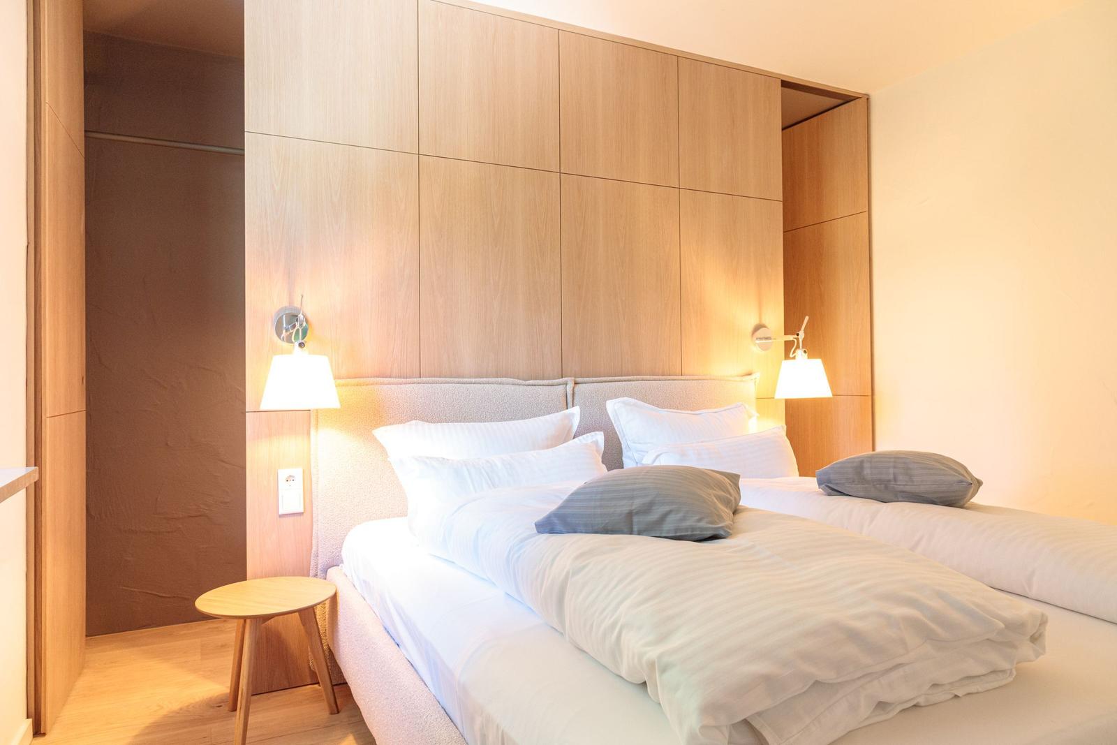 Schlafzimmer mit Doppelbett, Holzwand und Nachttisch