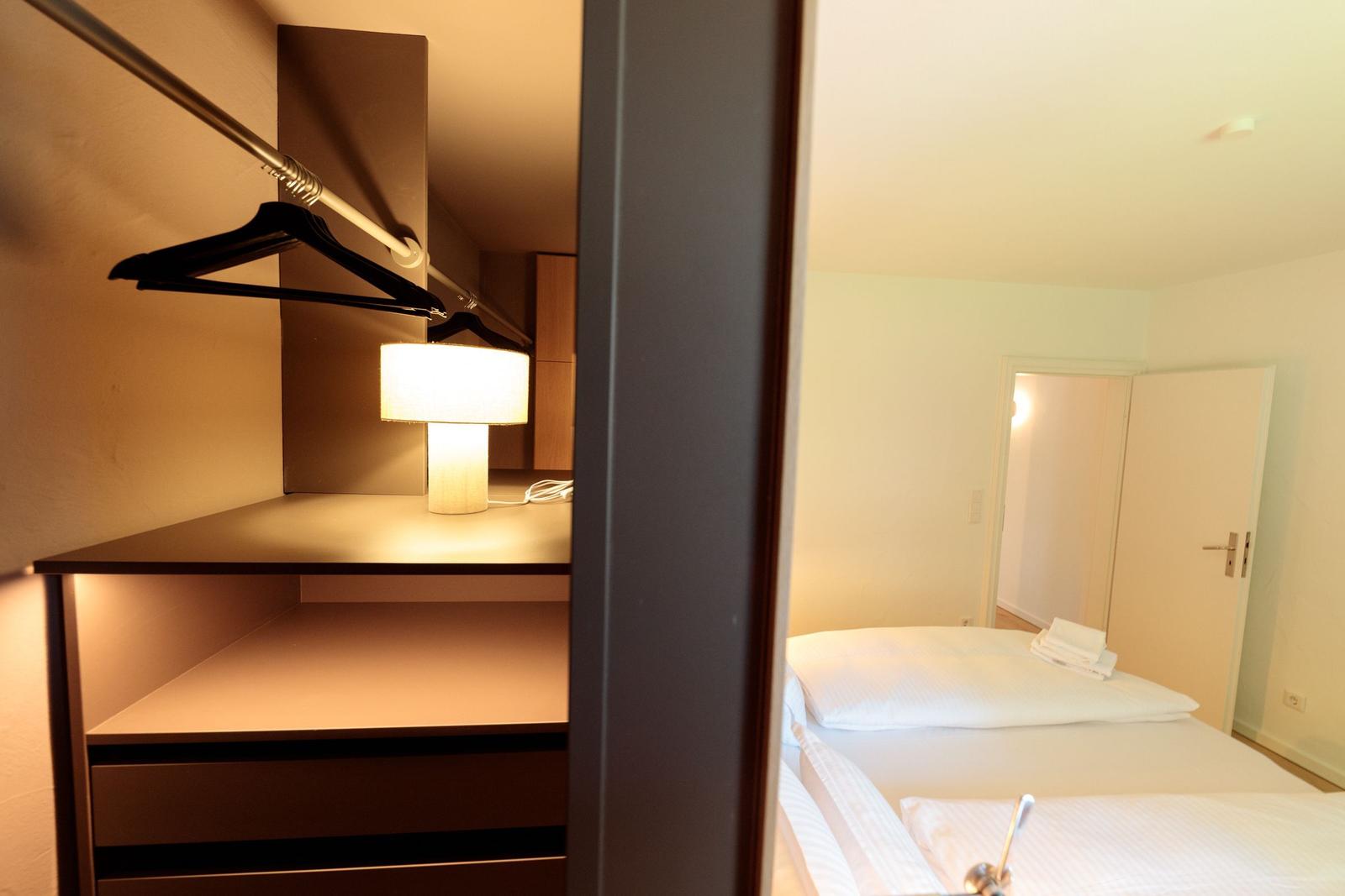 Schlafzimmer mit Bett, Kleiderschrank und Nachttischlampe.