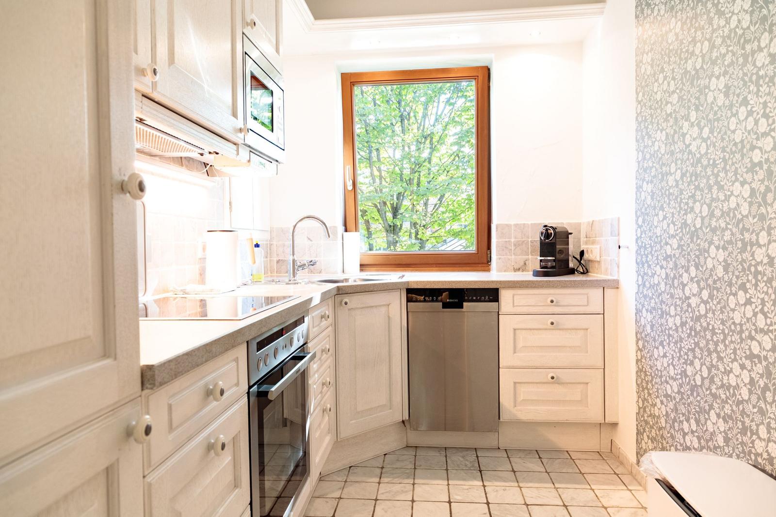 Küche mit Fenster, Spüle, Dunstabzug, Kaffeemaschine und Waschmaschine.