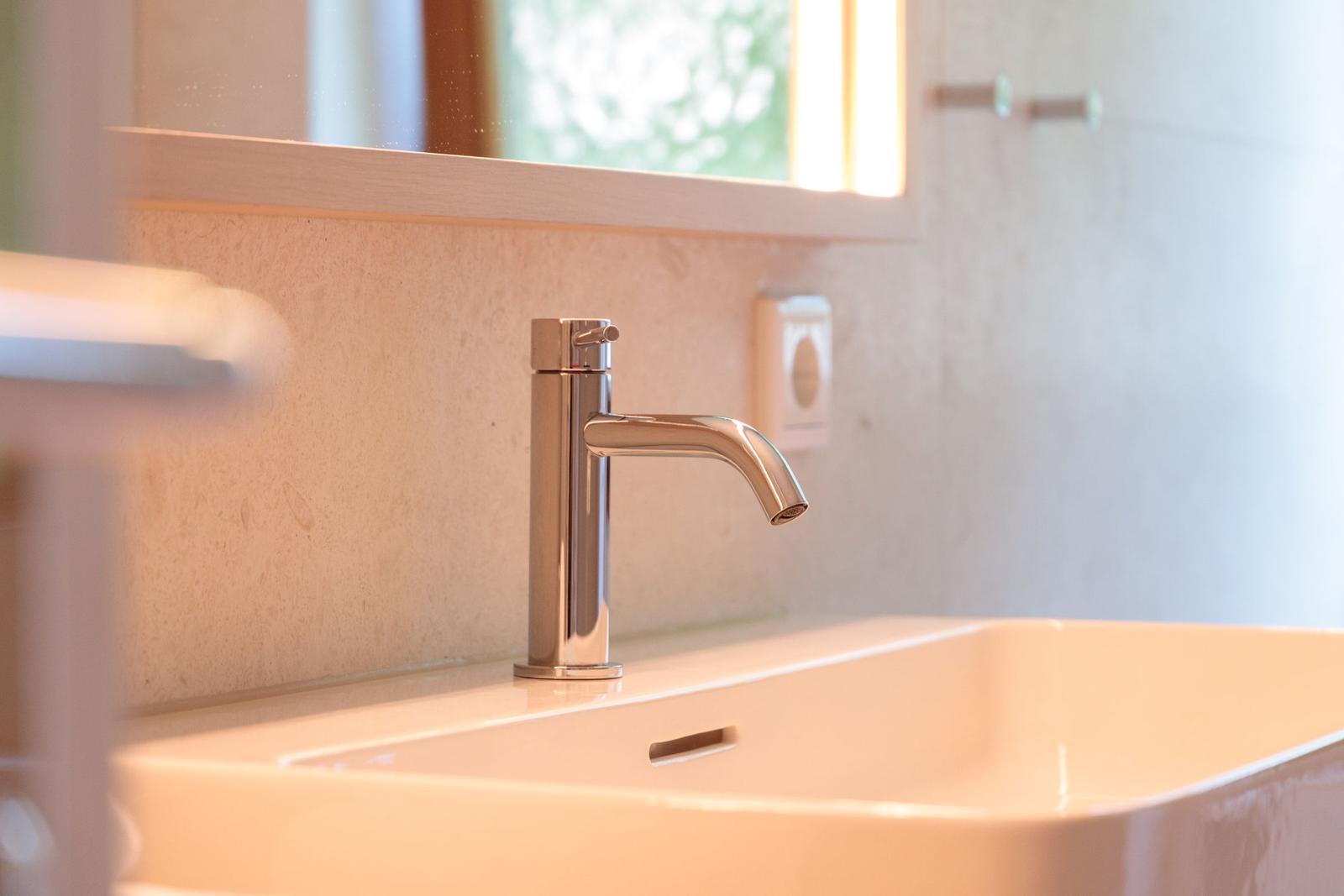 Waschbecken mit modernem Wasserhahn und Spiegelschrank