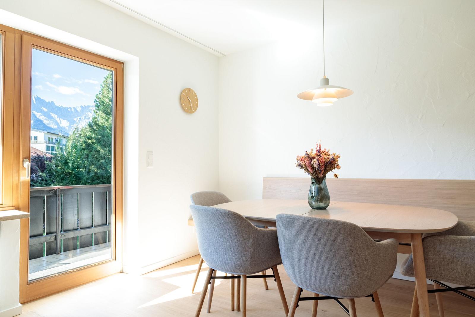 Esstisch mit Stühlen und Blick auf Balkon mit Bergblick.