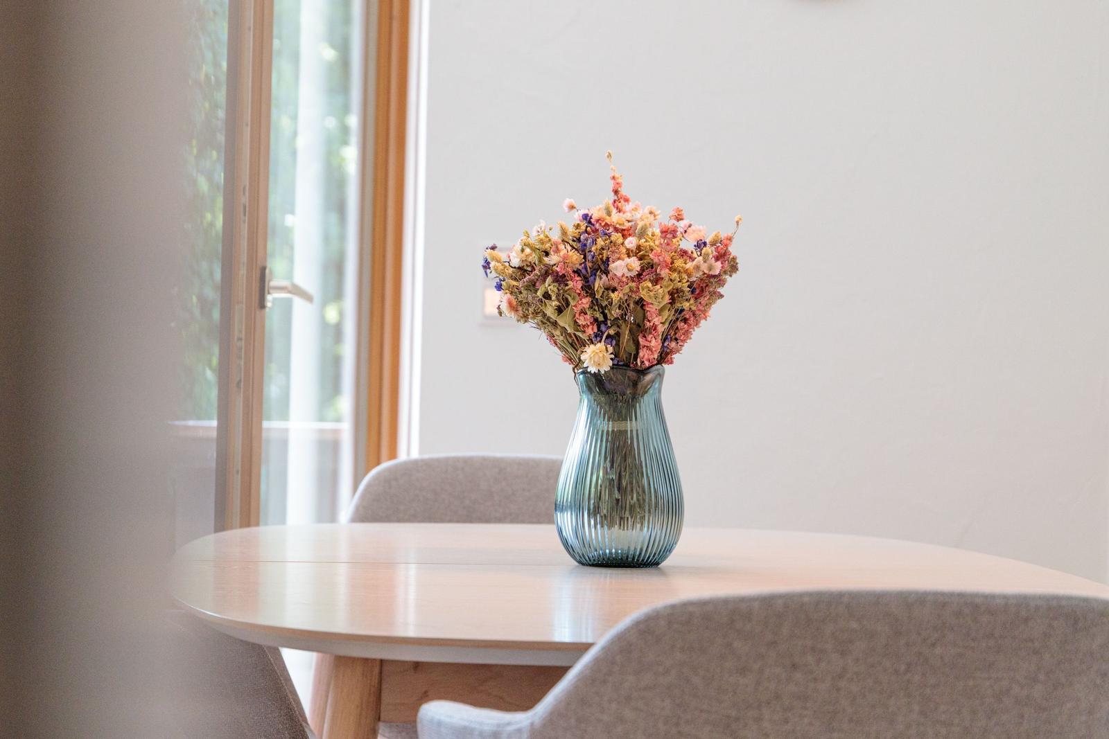 Ein runder Tisch mit Stühlen und einer Vase mit getrockneten Blumen.