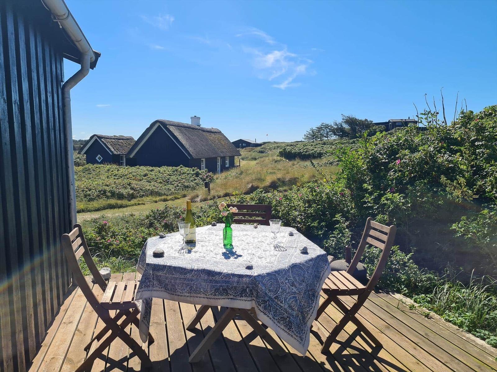 Deck with table and chairs. View of traditional houses and green areas.