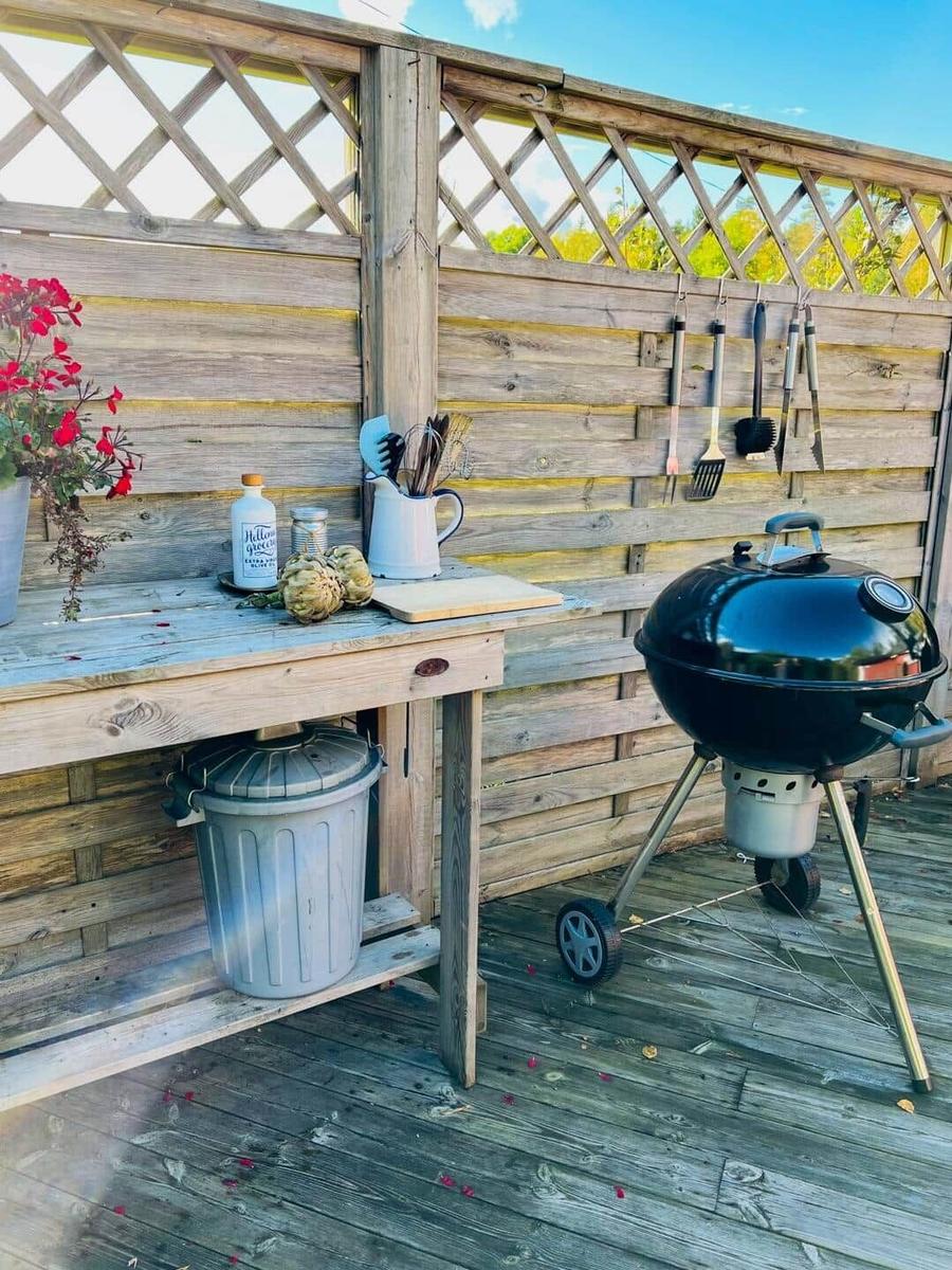 Außenbereich mit Grill, Küchenzeile und Grillwerkzeugen an der Wand.