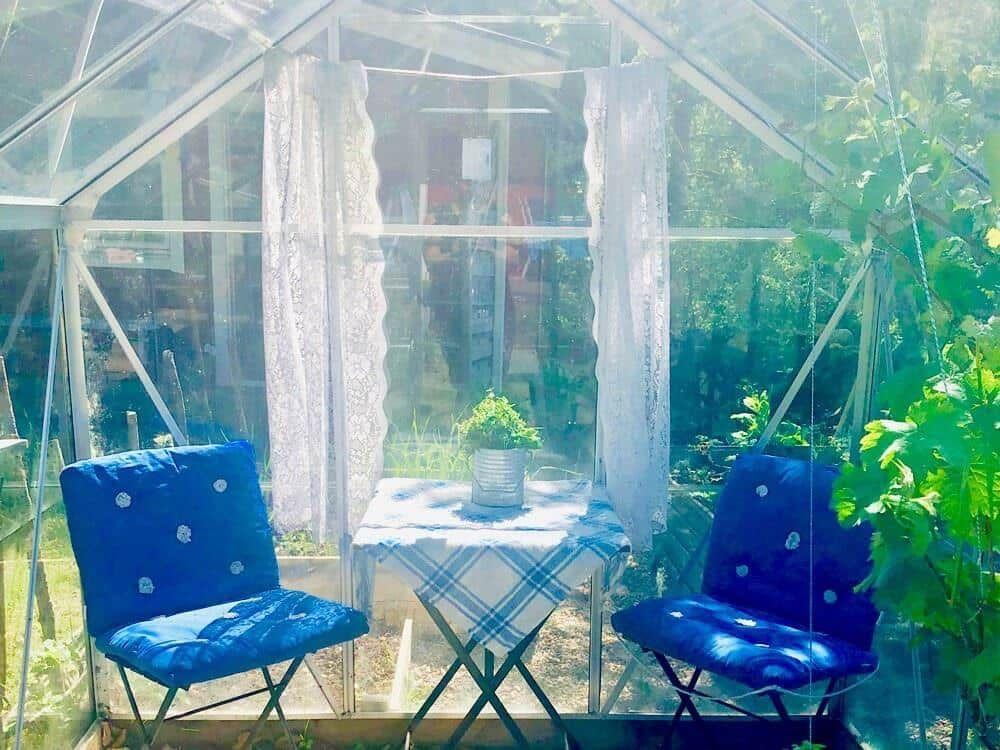 Zwei blaue Stühle und ein Tisch mit Tischdecke in einer Glasstruktur.