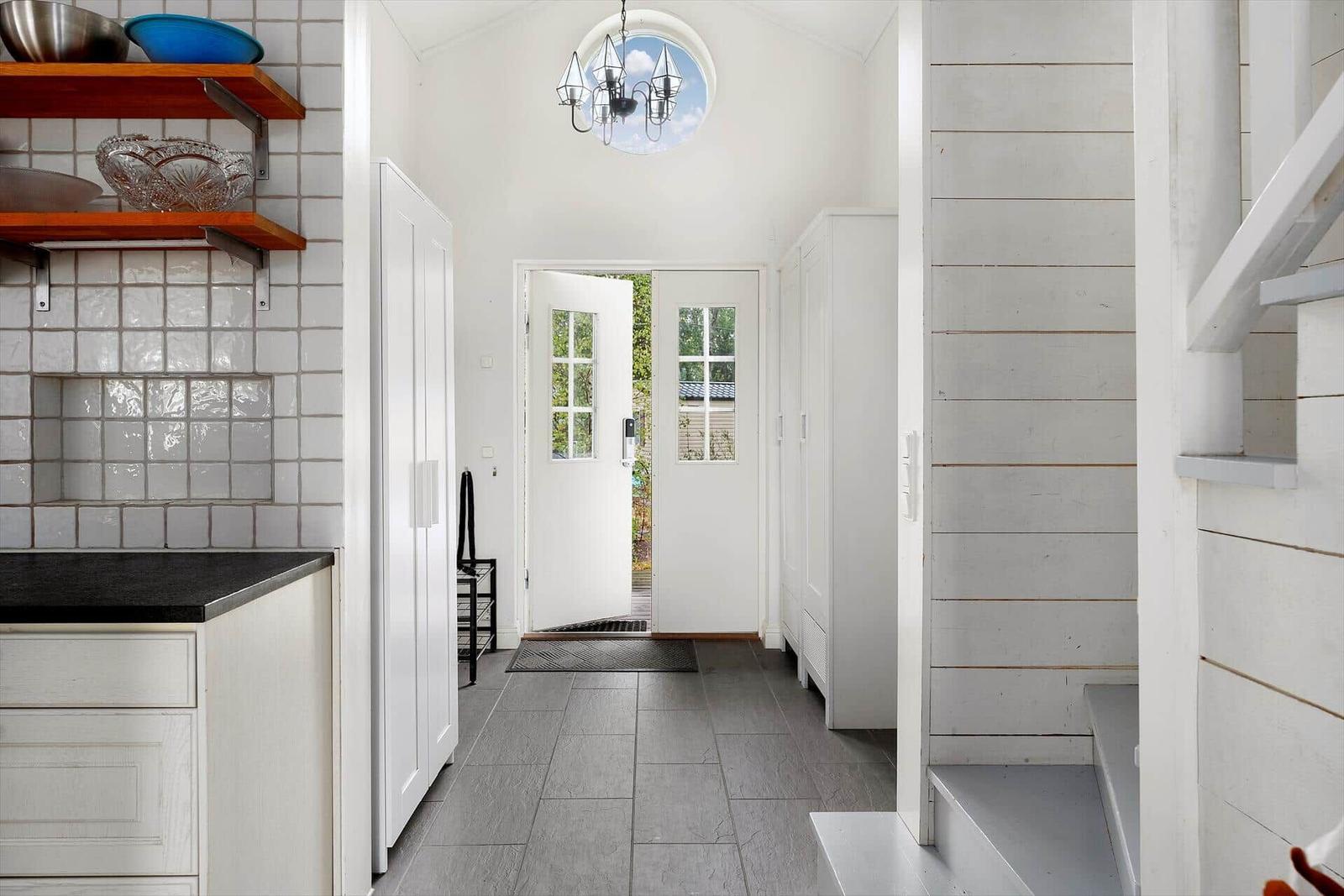 Küche mit Arbeitsplatte und Schränken, Flur mit Tür und Treppenhaus.
