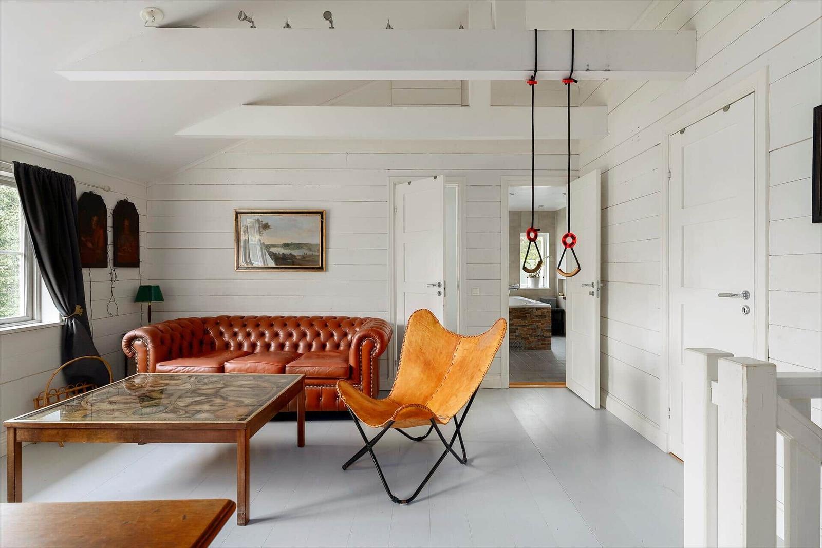 Wohnzimmer mit Ledersofa, Schwebestuhl und Hängematten.