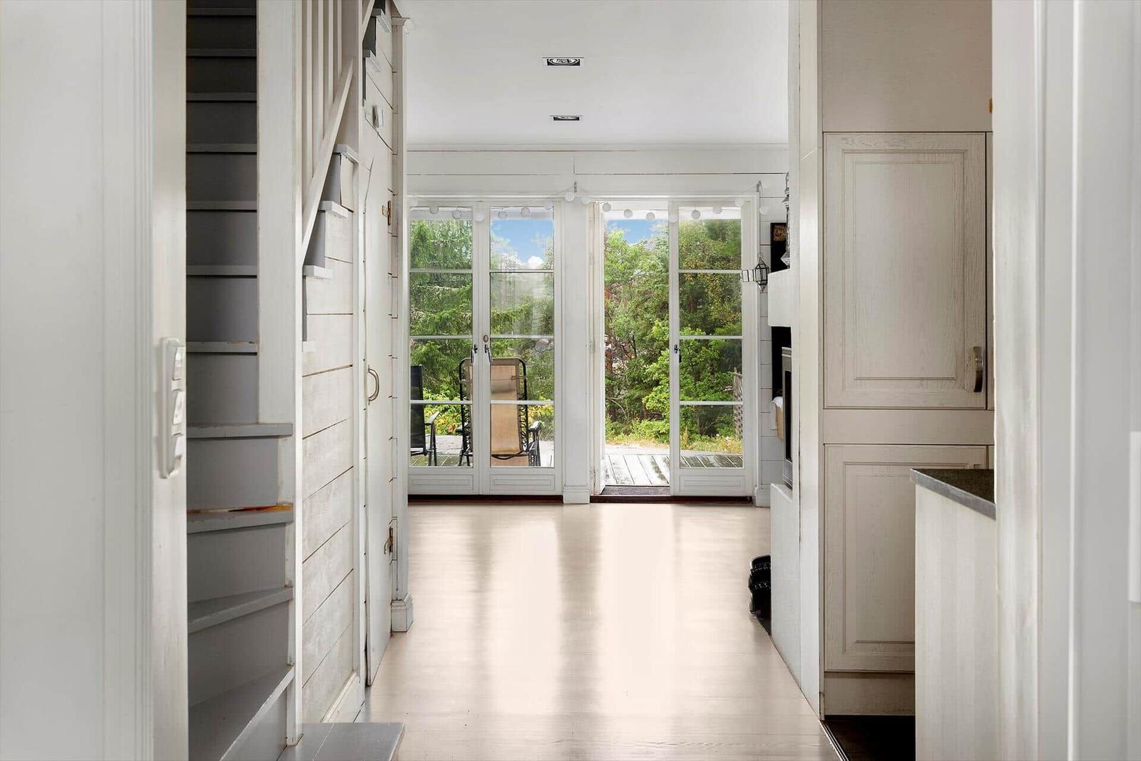Helle Eingangshalle mit Blick auf Terrasse und Wald.