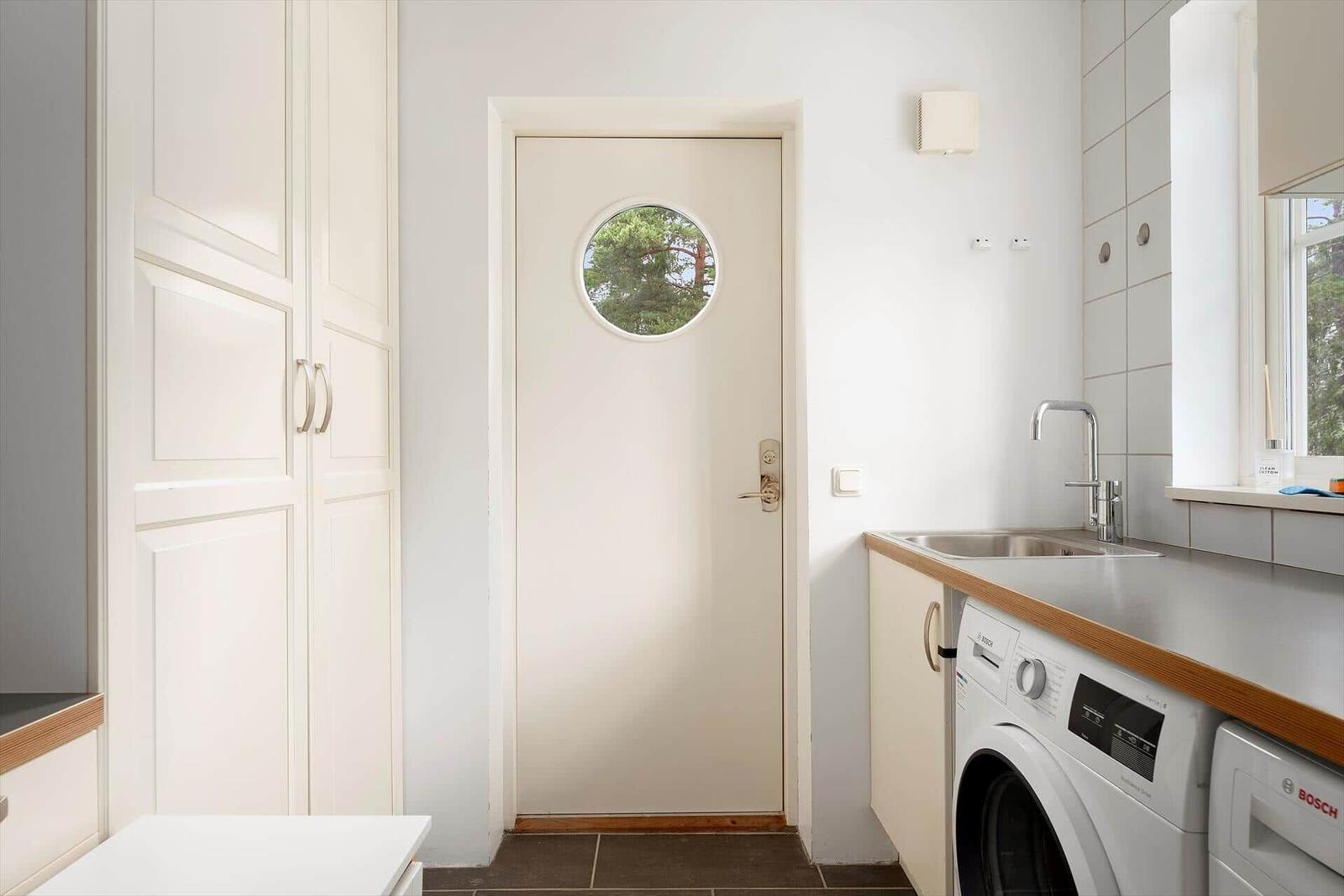 Helle Küche mit Waschmaschine und Tür mit runden Fenster
