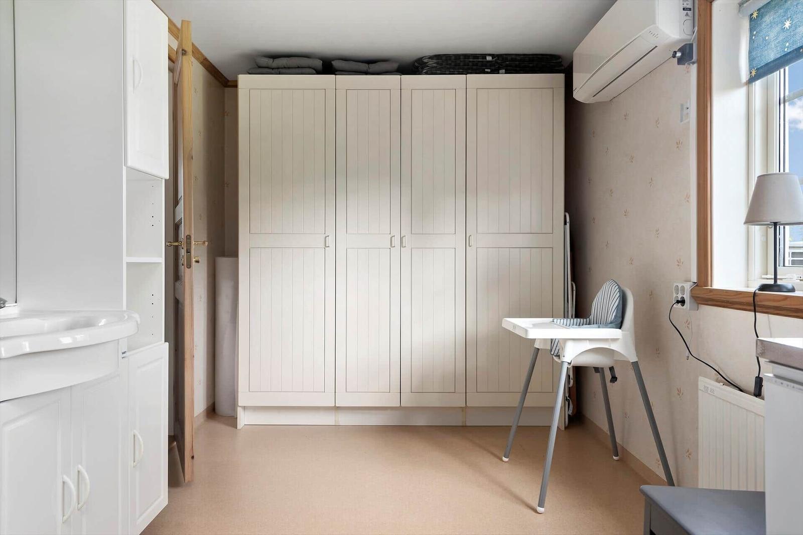 Kleines Zimmer mit Kleiderschrank, Hochstuhl und Fenster