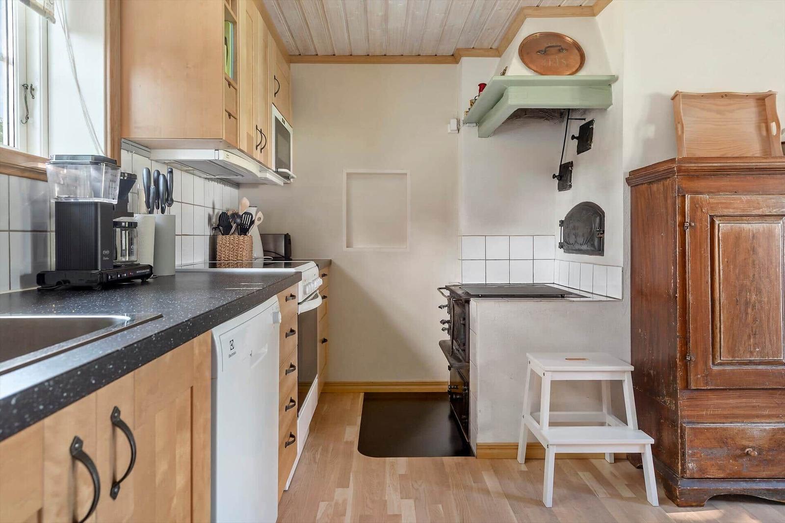 Küche mit Holzmöbeln, Steinplatten und altem Ofen