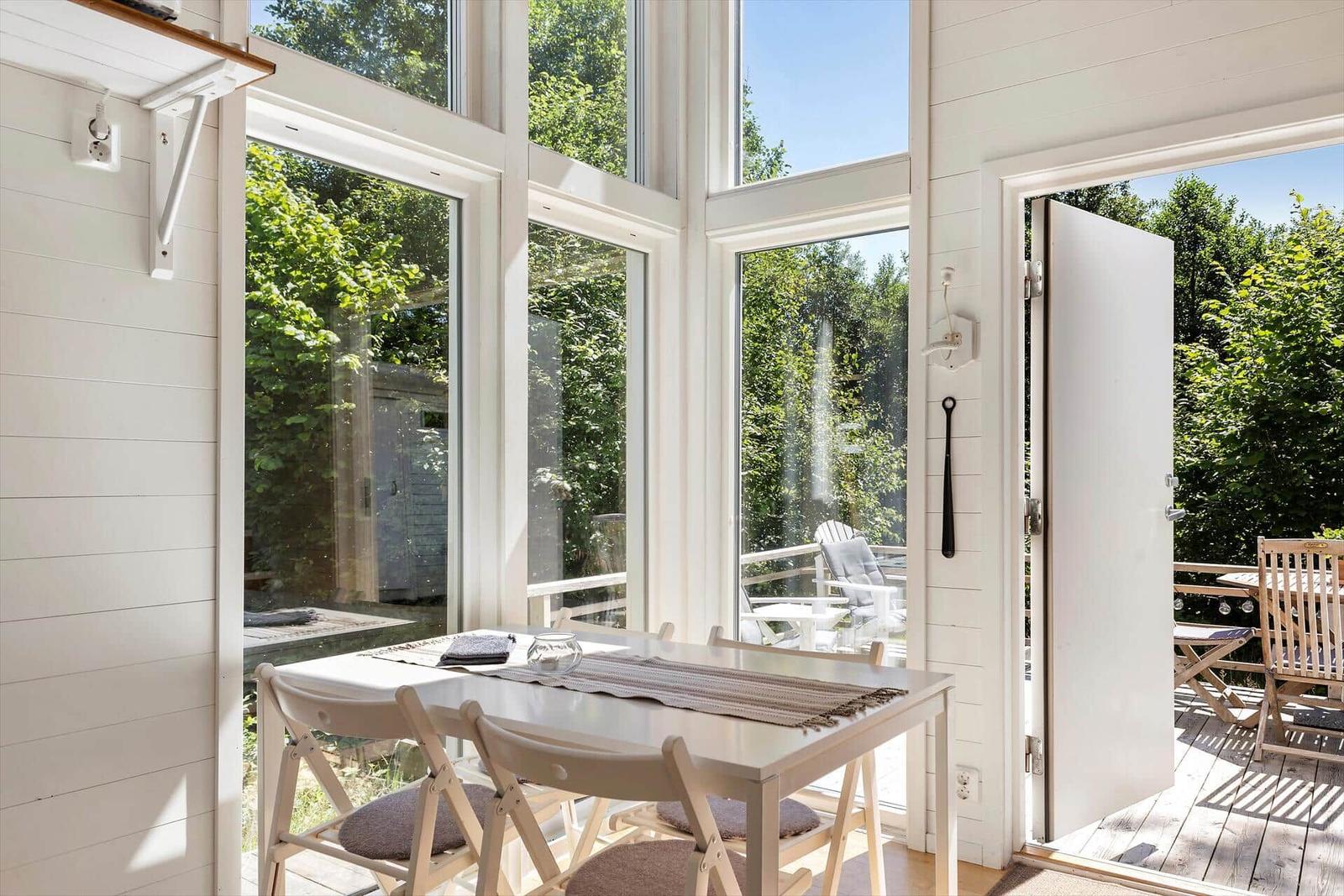 Essbereich mit Tisch und Stühlen, große Fenster, Blick auf Terrasse und Garten.