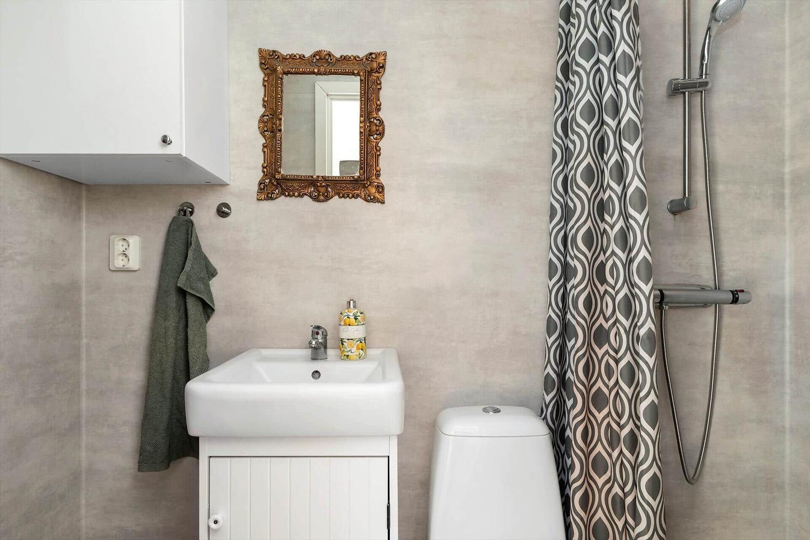 Badezimmer mit Waschbecken, Toilette und Dusche mit Vorhang.