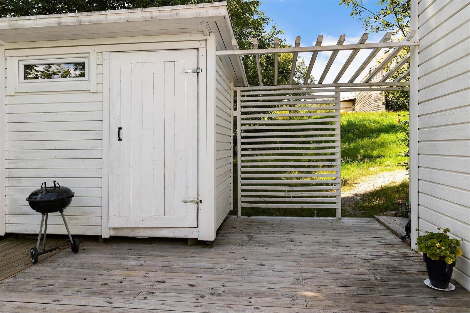 Weiße Holzgarage mit Grill und Pergola auf Holzterrasse
