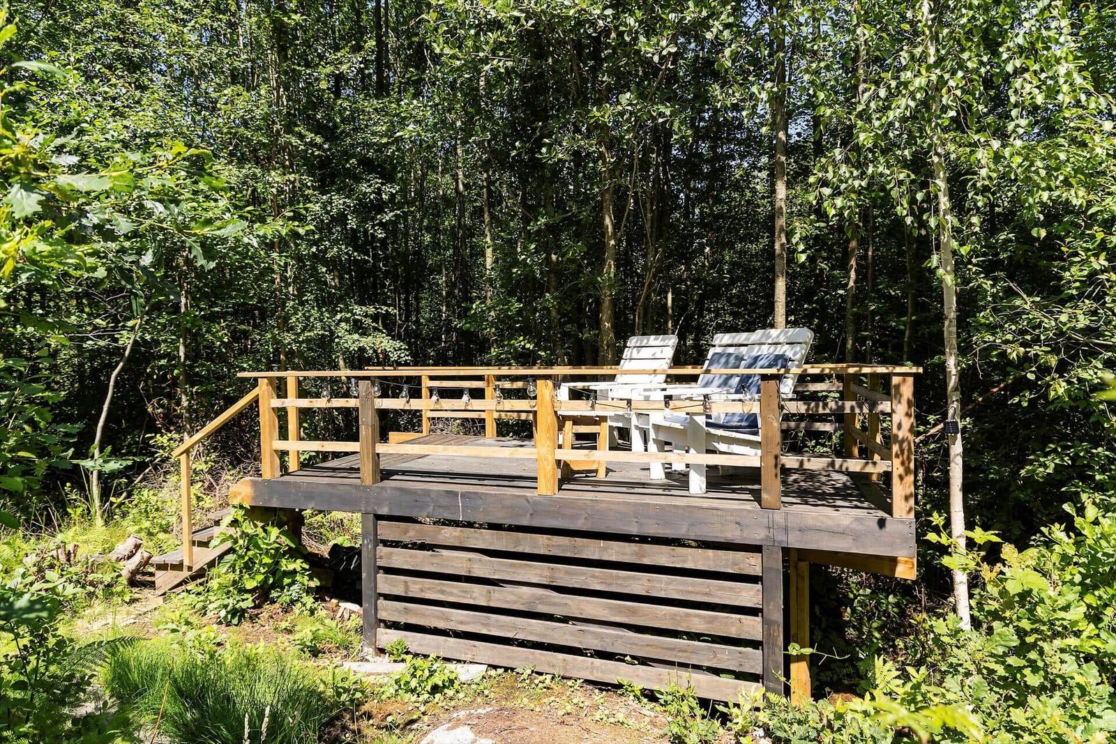 Holzterrasse mit Liegestühlen im Wald