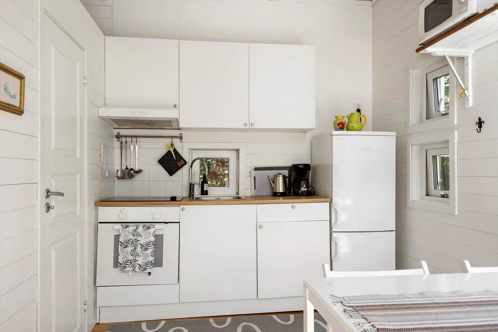 Küche mit weißen Schränken, Kühlschrank und Kochfeld.