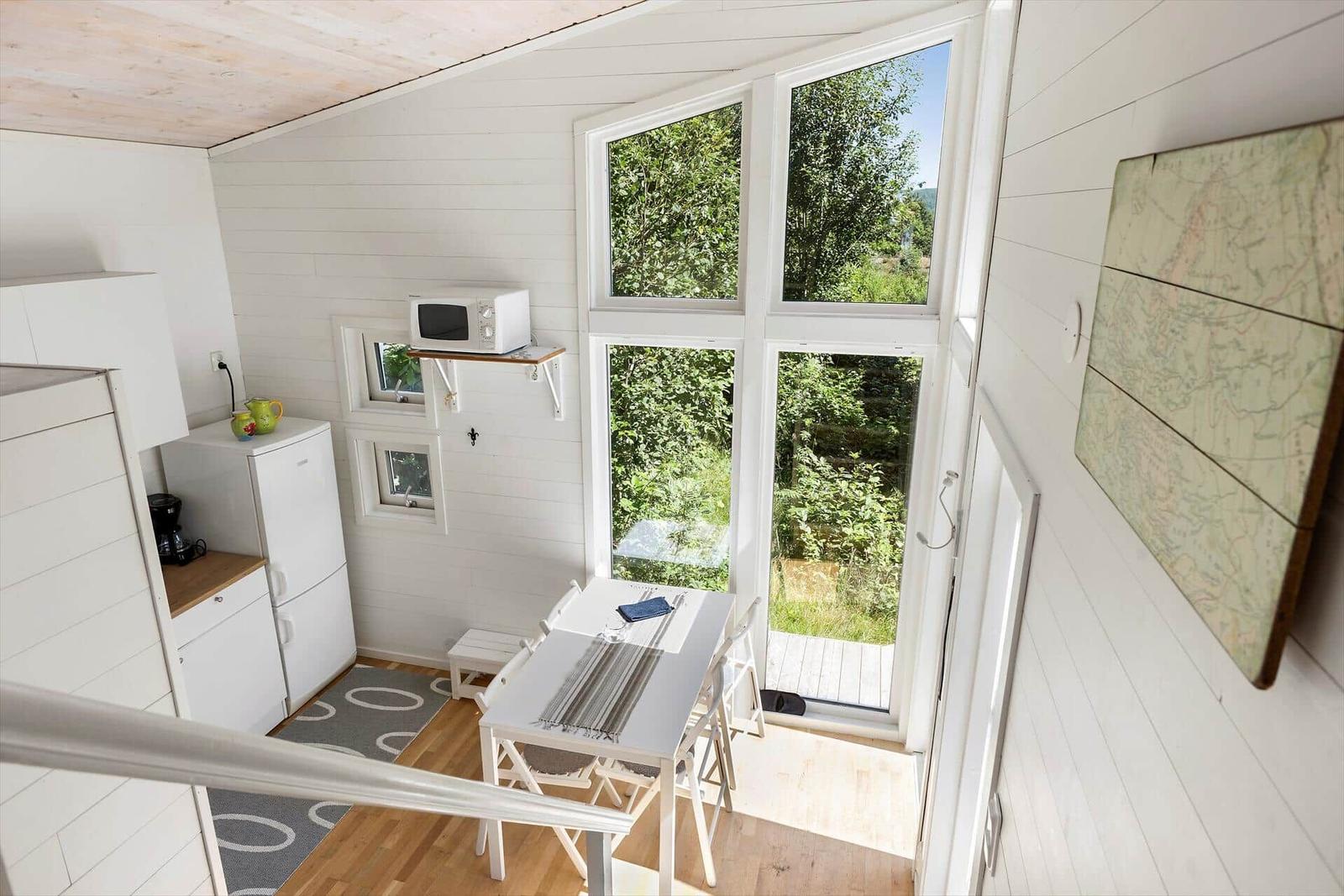 Küche mit Tisch, Fenster und Kühlschrank. Wandbild und Holzboden.