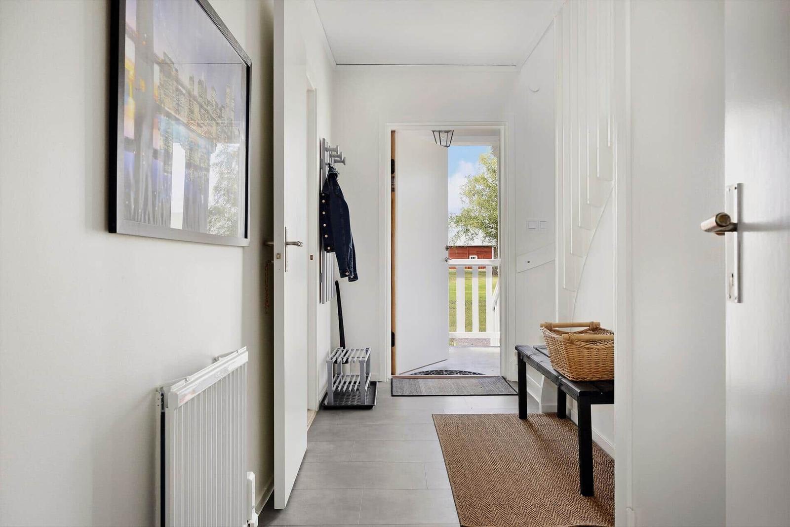 Flur mit Wandbild, Garderobe und Eingangstür zum Balkon.