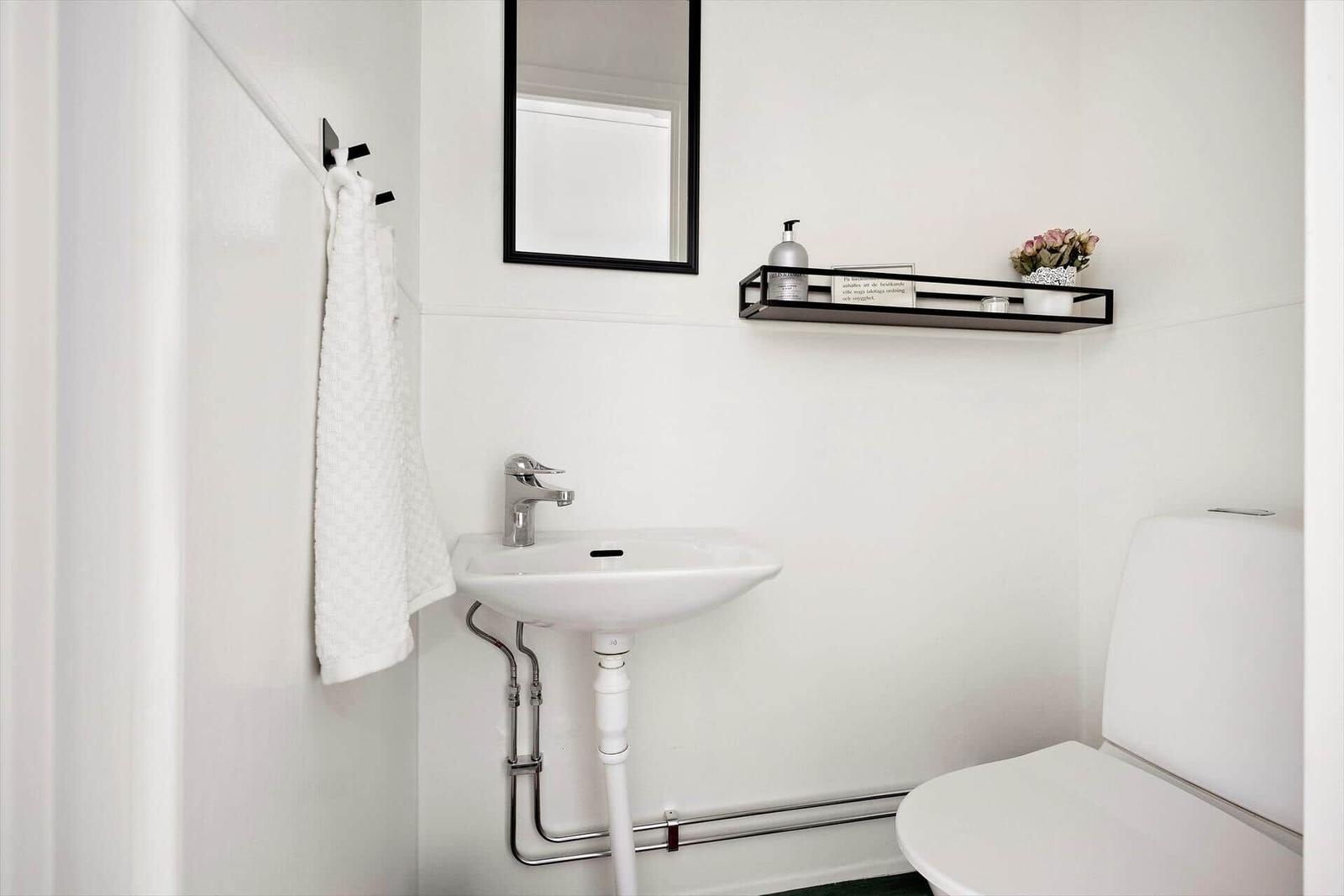 Badezimmer mit Waschbecken, Spiegel, Handtuch und Toilette.