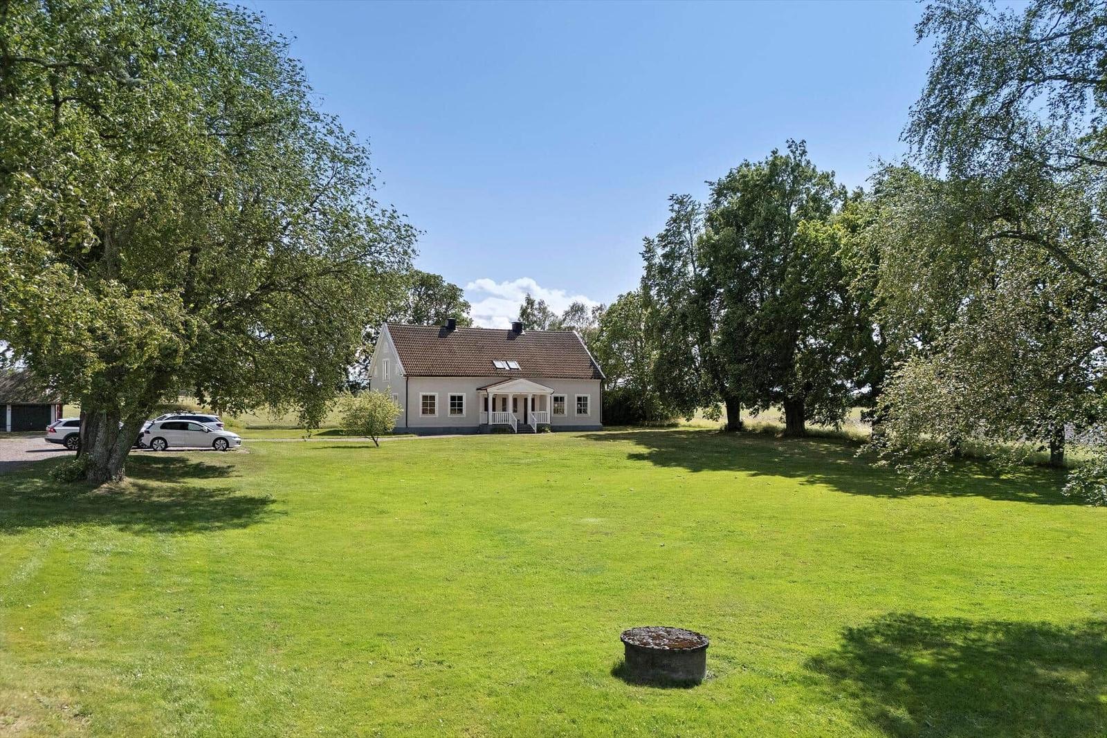Haus mit großem Garten, Bäumen und Parkplatz. 