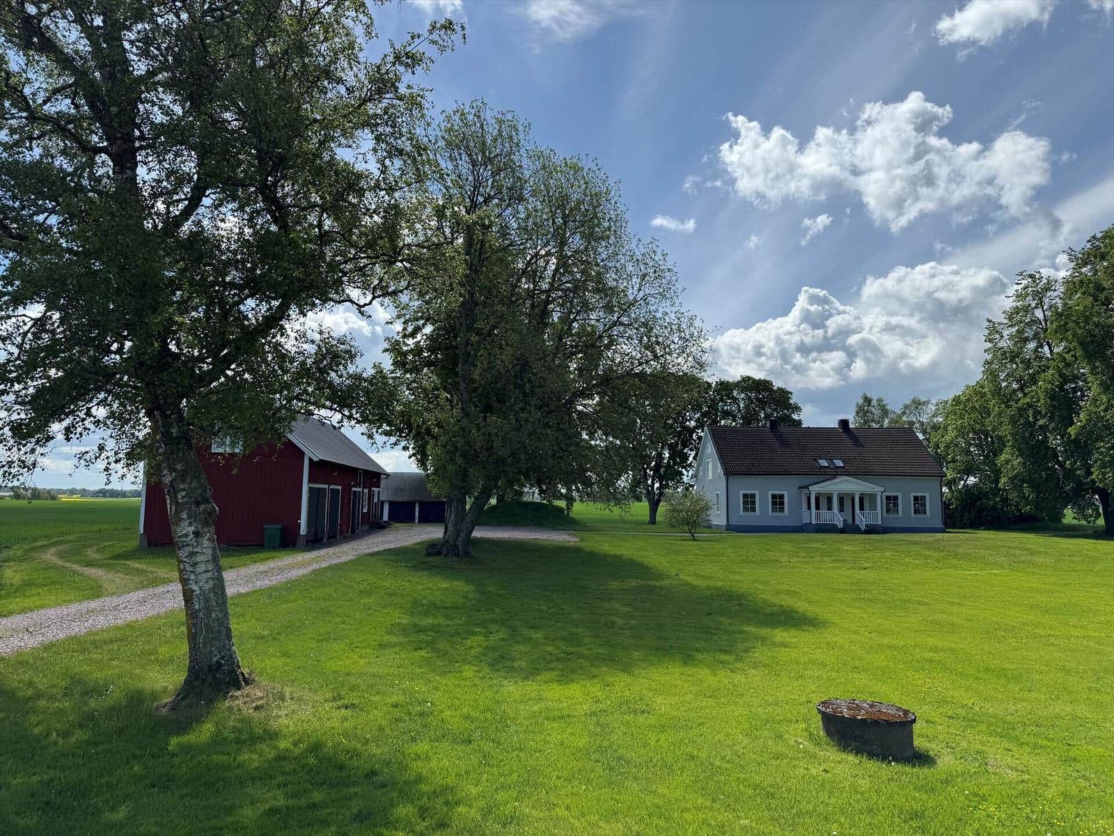 Haus mit rotem Schuppen und grünem Rasen unter blauem Himmel.