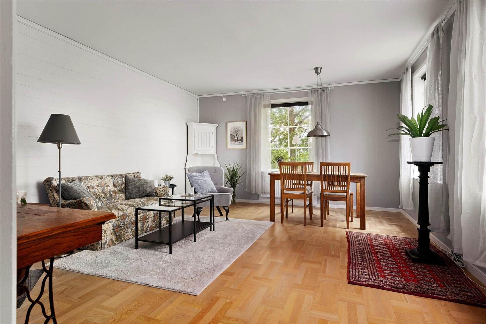 Wohn- und Essbereich mit Holzboden, Sofa, Tisch und Stühlen.