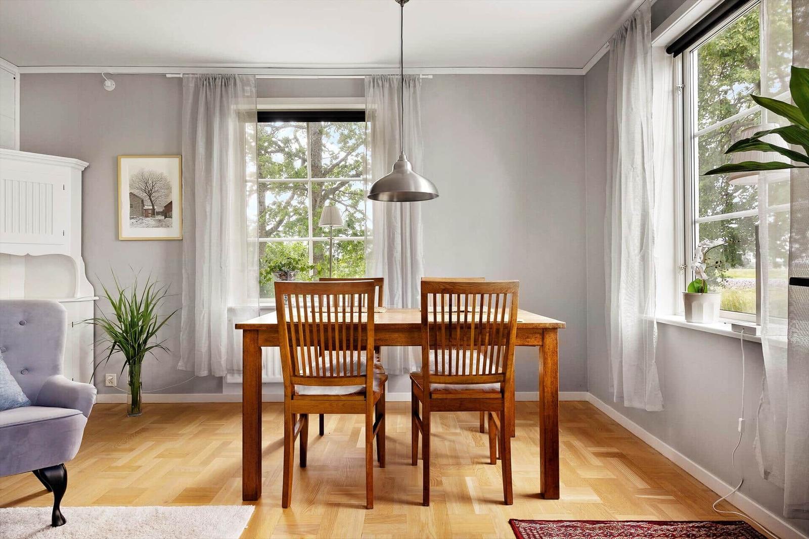 Esszimmer mit Holztisch, Stühlen und Fenstern mit Blick auf Grün