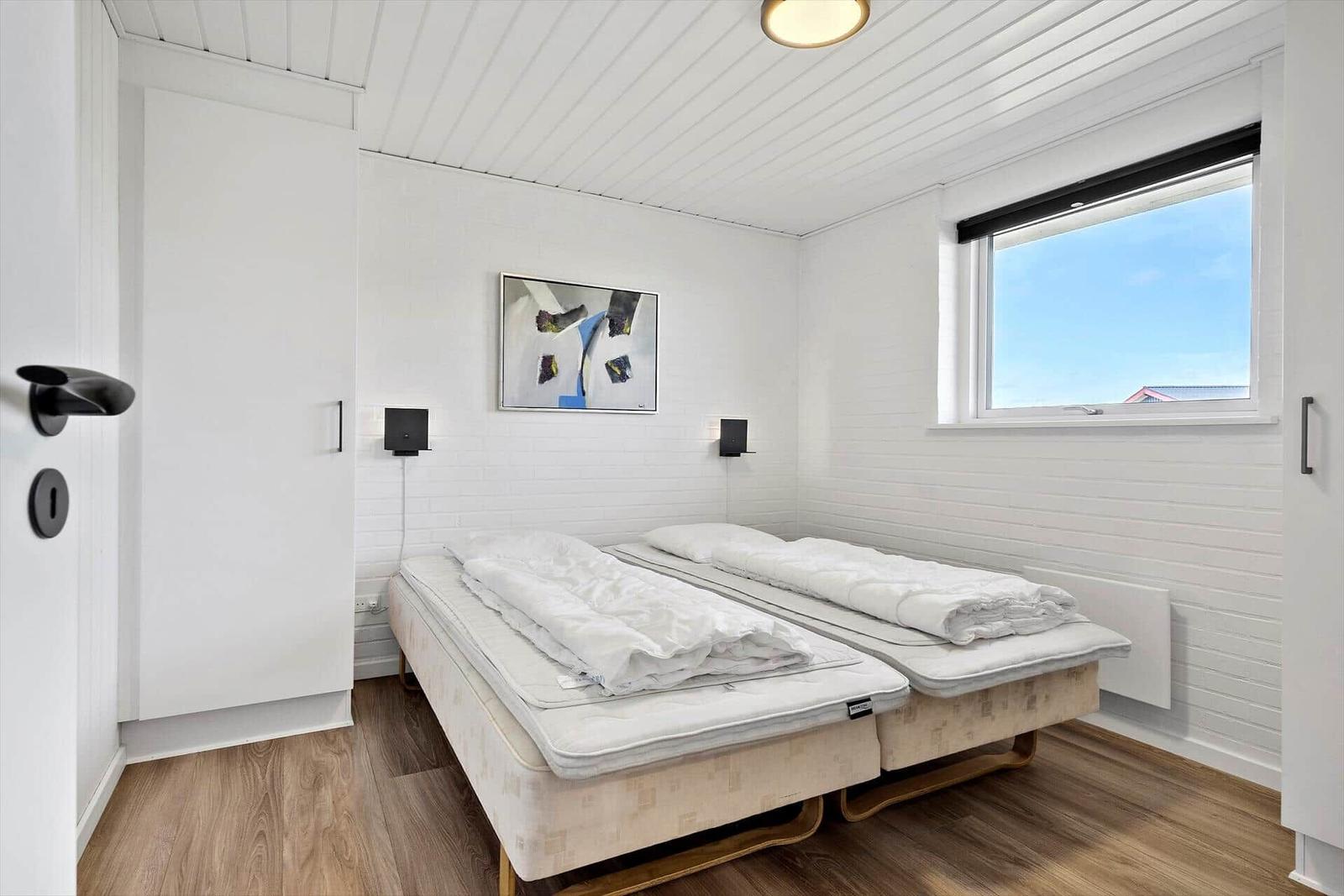 Bedroom with two beds, window, and wall art.