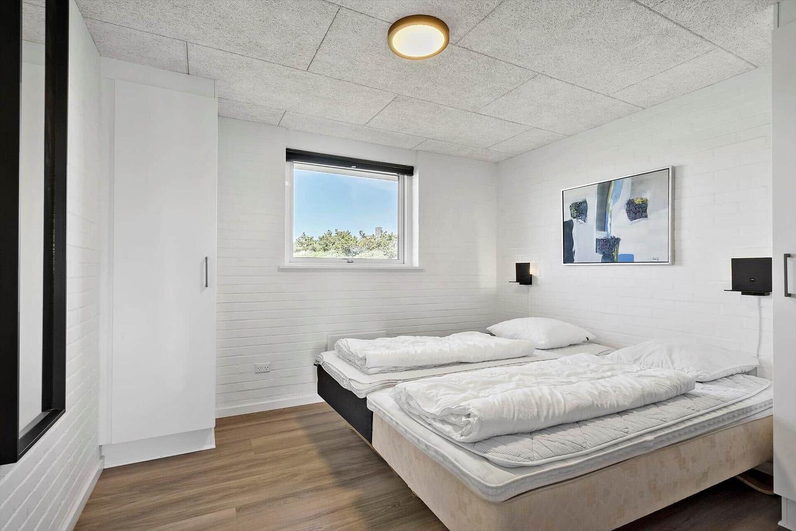 Bedroom with double bed, window, and wall art.