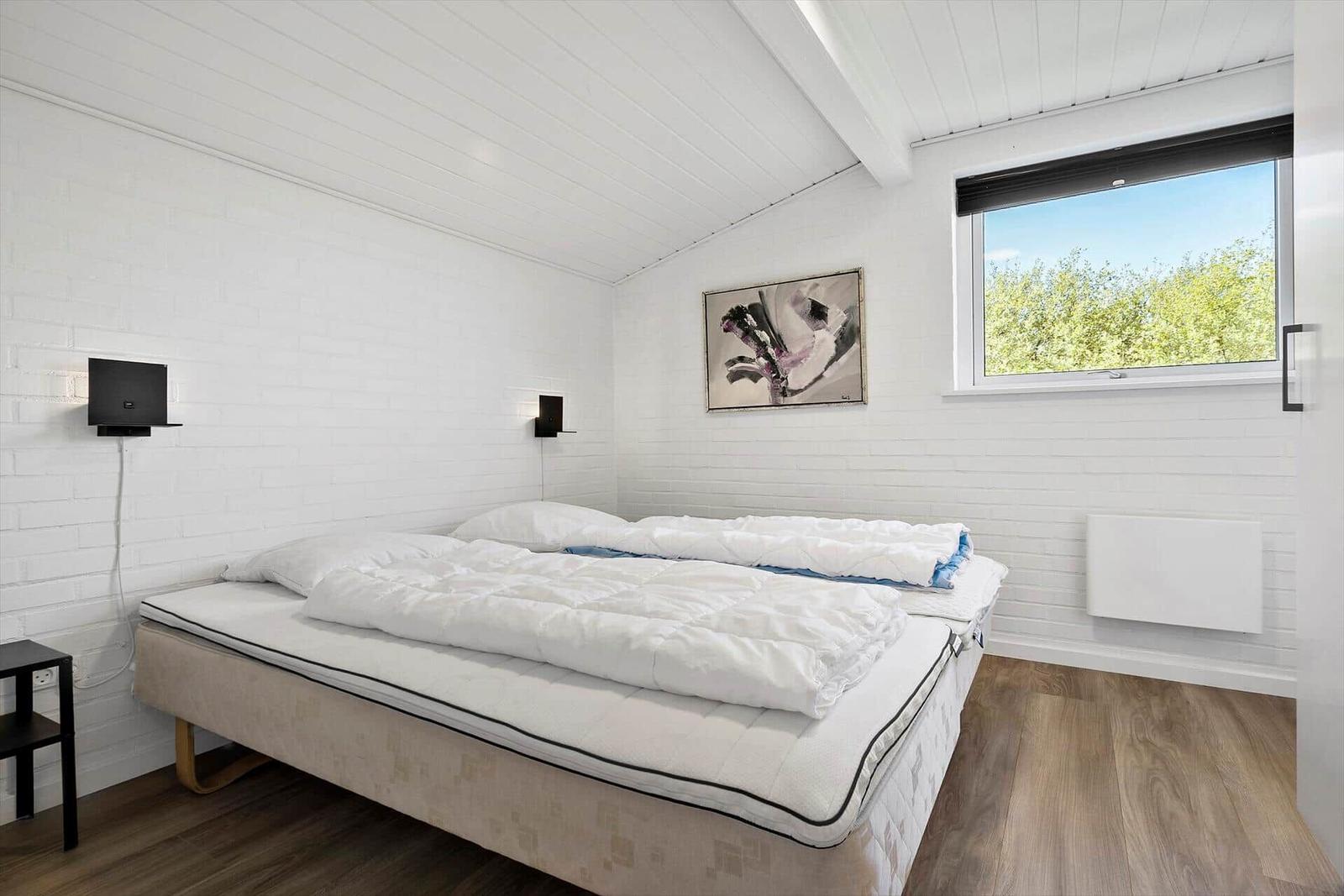 Bedroom with double bed, window, and wall art.