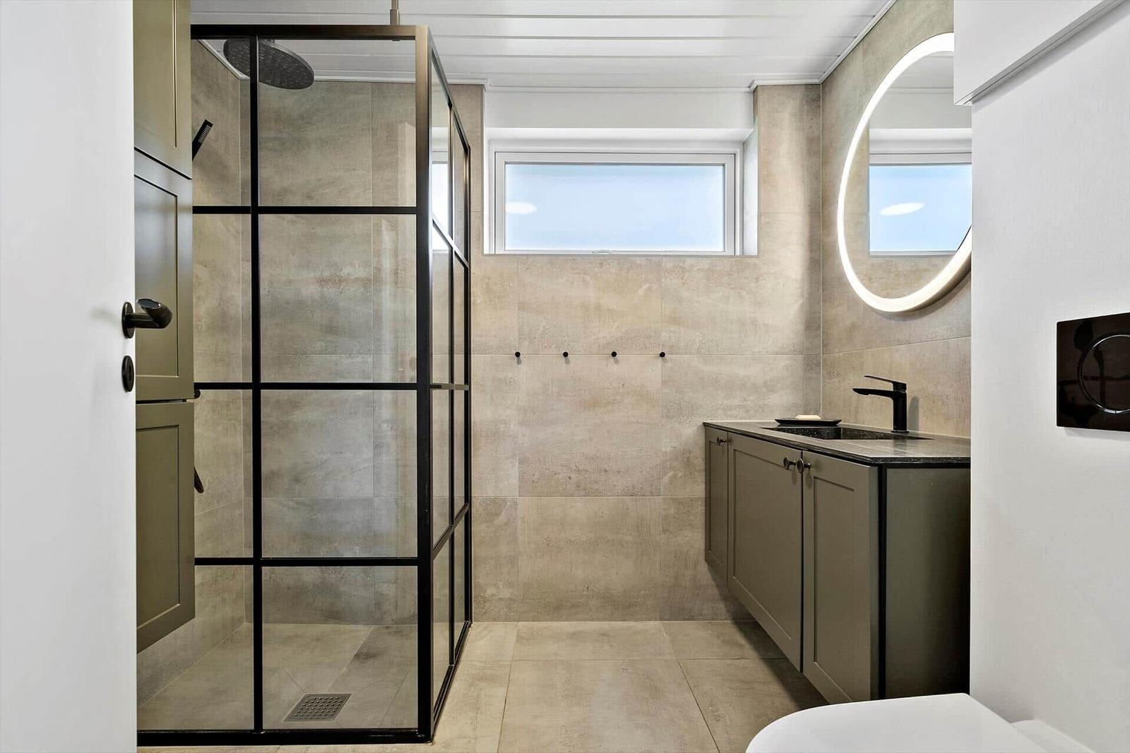 Bathroom with shower, sink, and round mirror