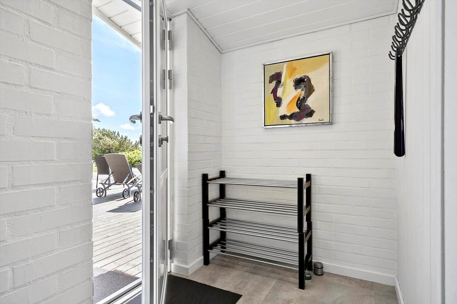 Entrance with shoe rack, wall art, and view of terrace.