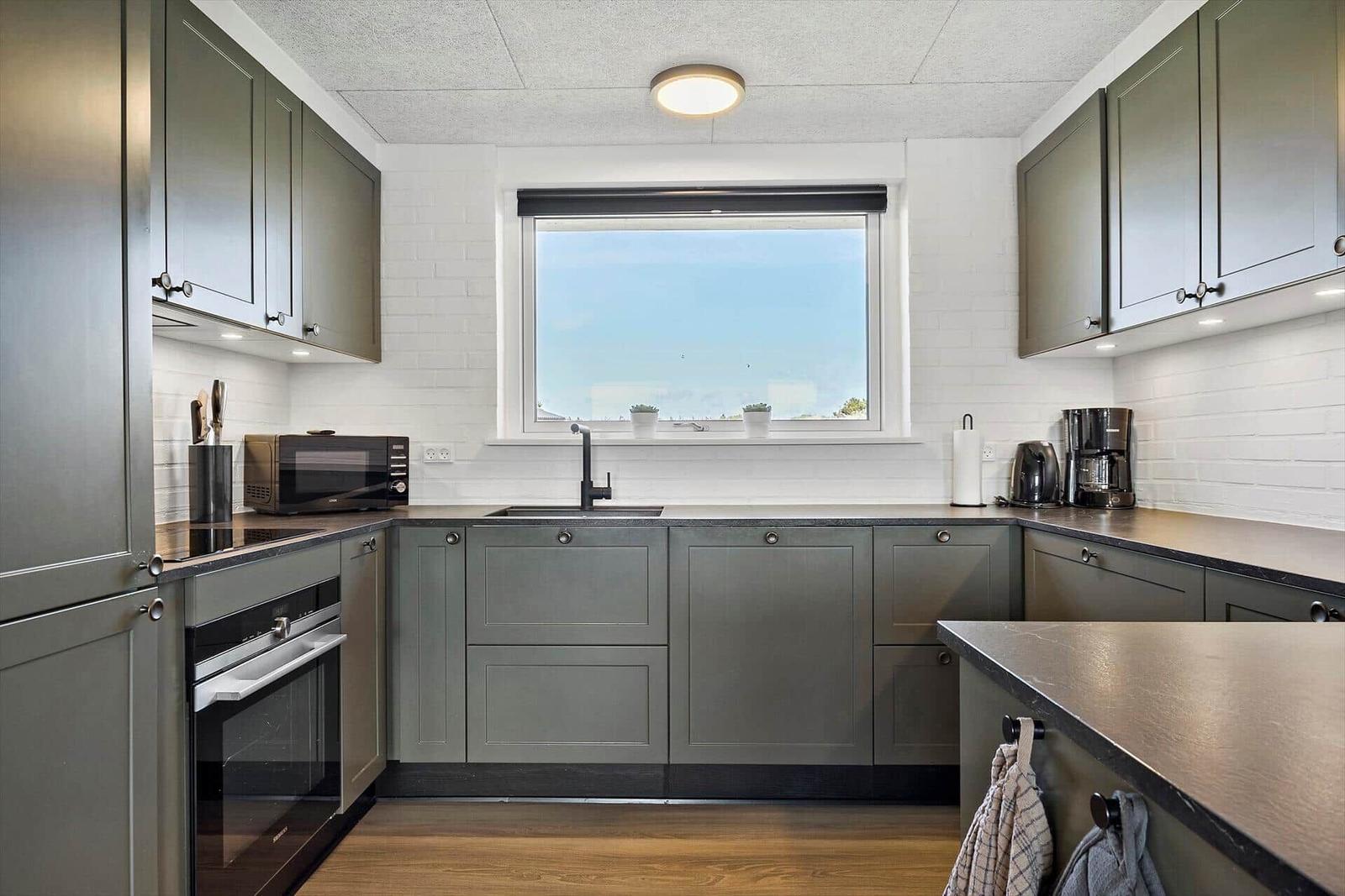 Kitchen with gray cabinets, countertop, and window with view.