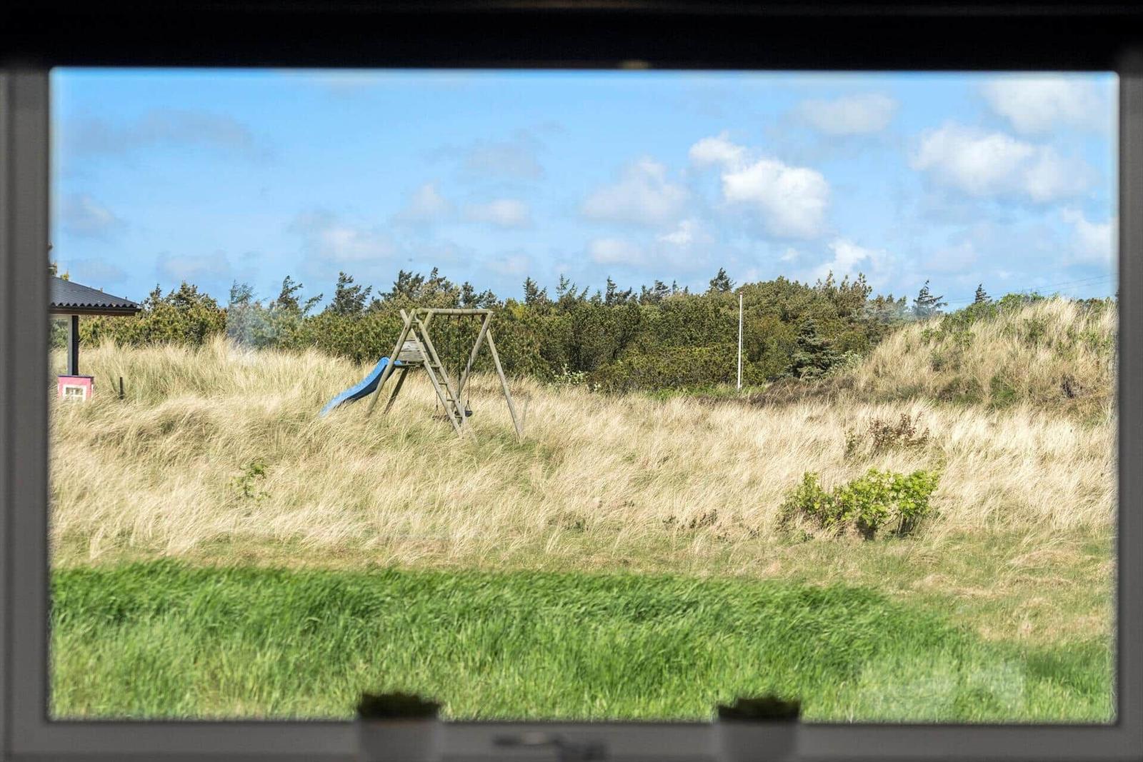 Through the window, a playground with slide and swing is visible in the grass.