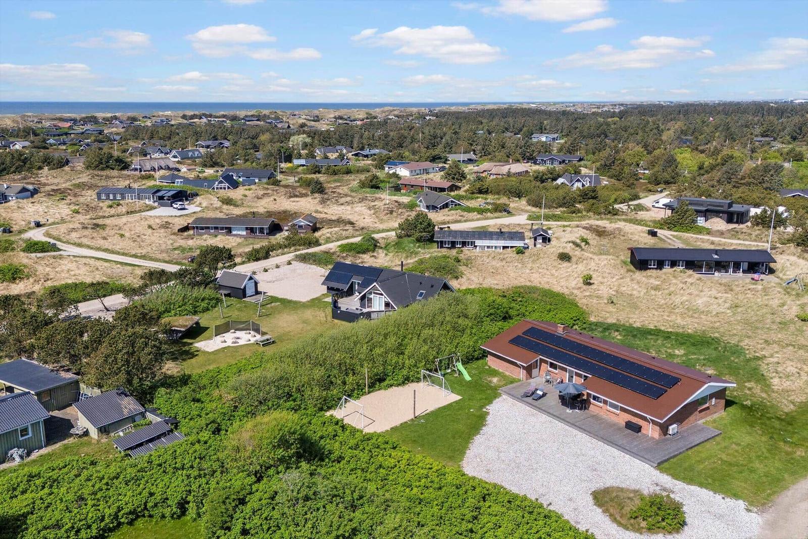 House with solar panels, garden, and coastal view.