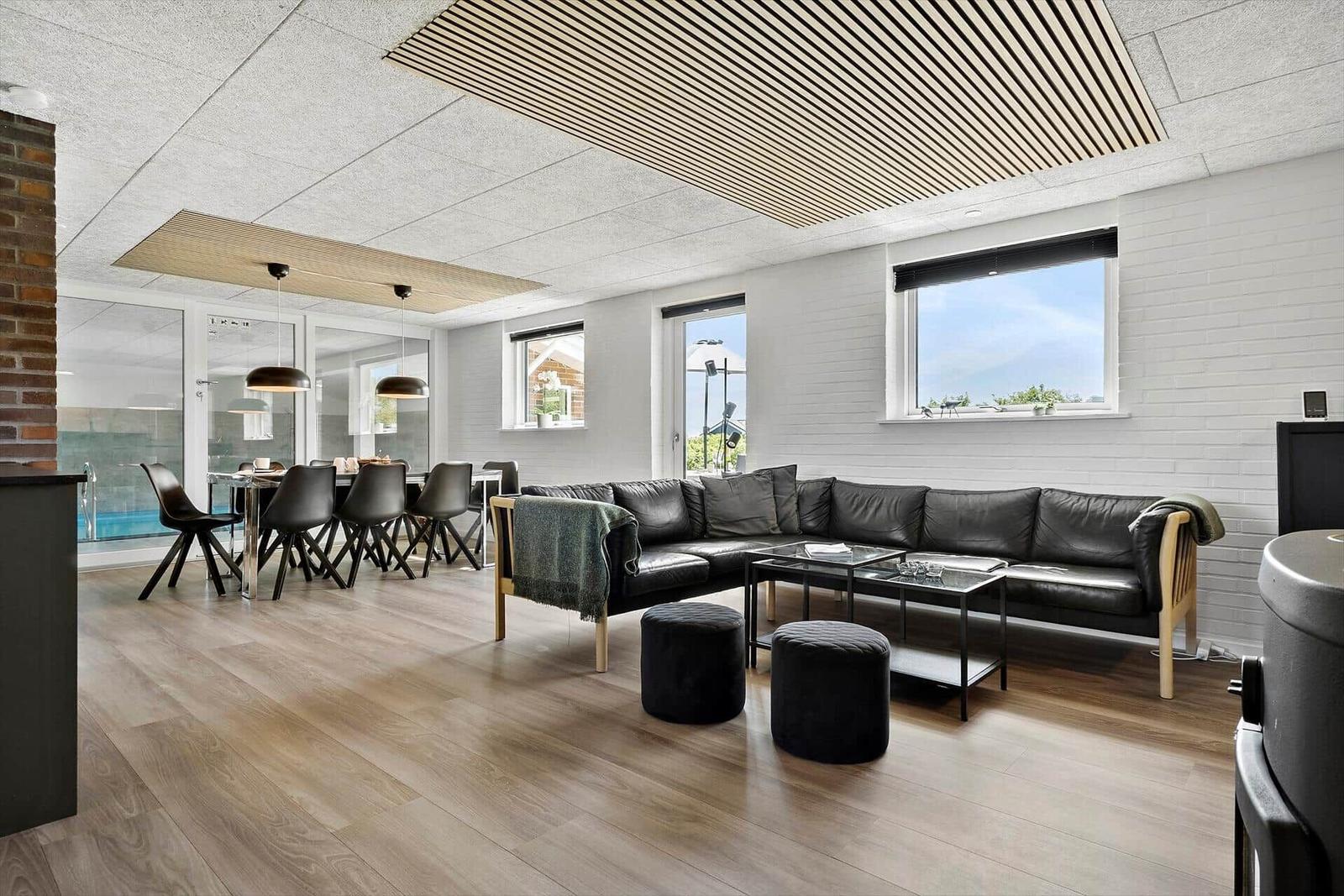 Living and dining area with sofa, table and chairs. Wooden floor and white walls.