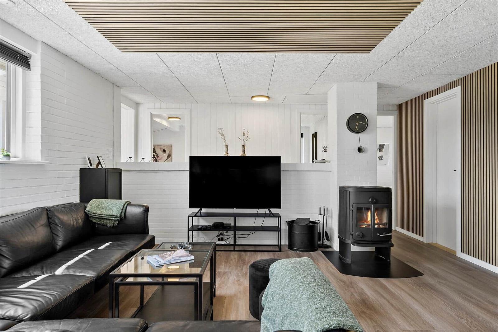 Living room with sofa, TV, and wood stove.