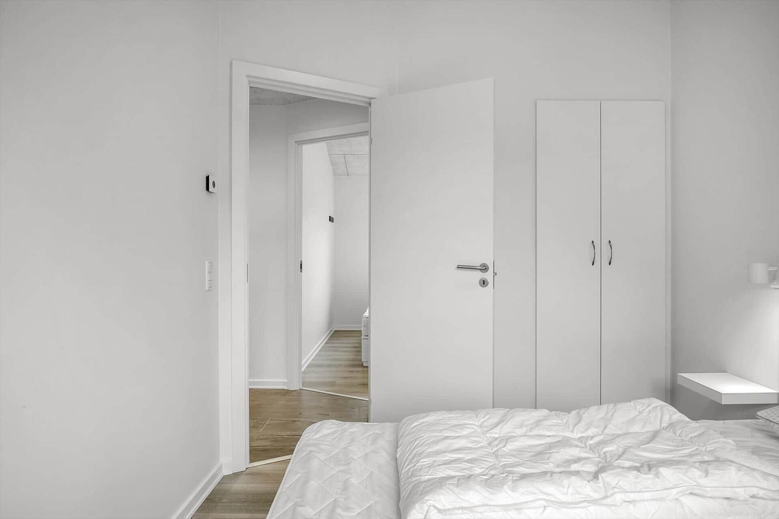 Bedroom with bed, wardrobe, and door to hallway.