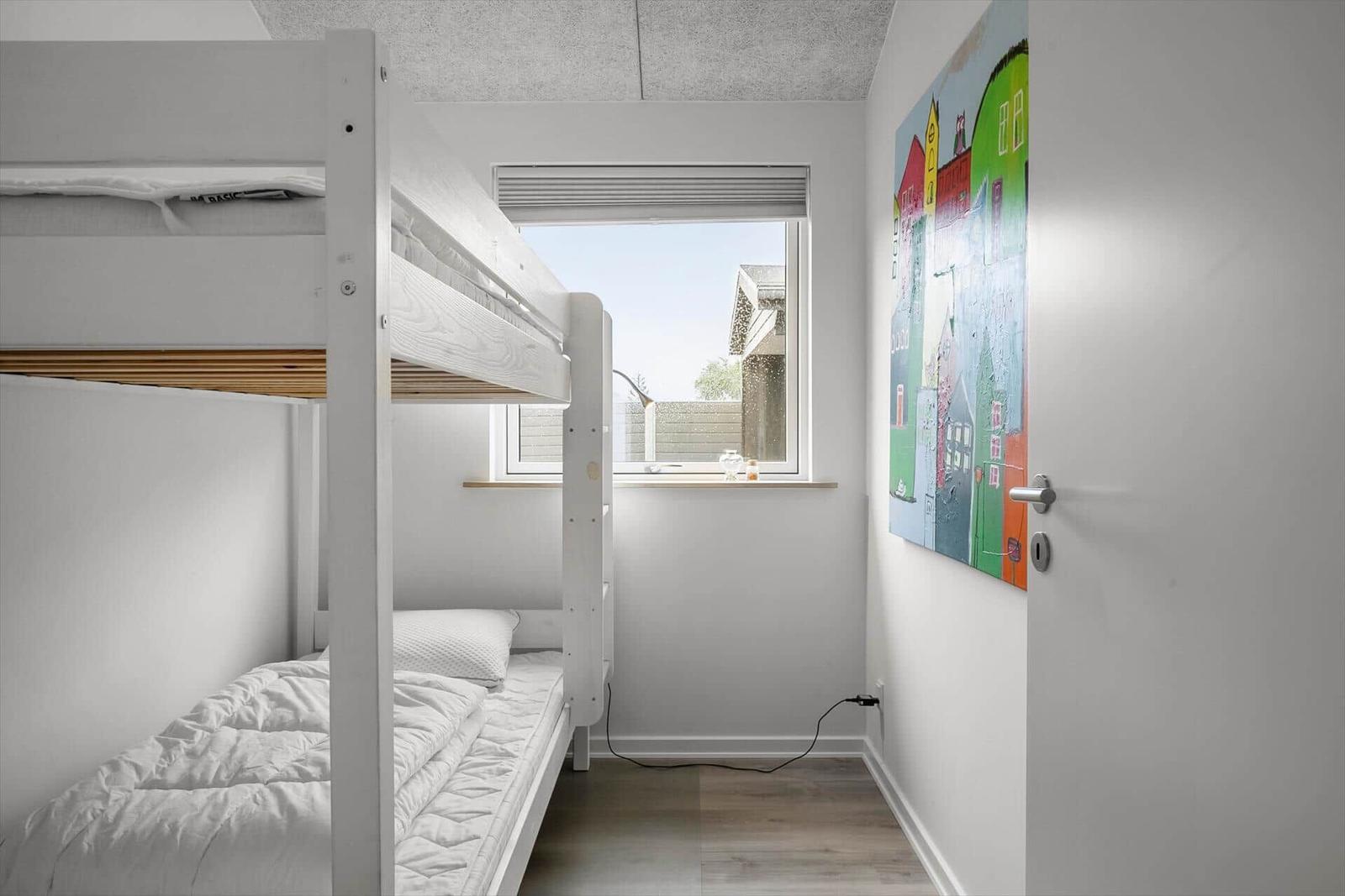 Room with bunk bed, window, and wall art.