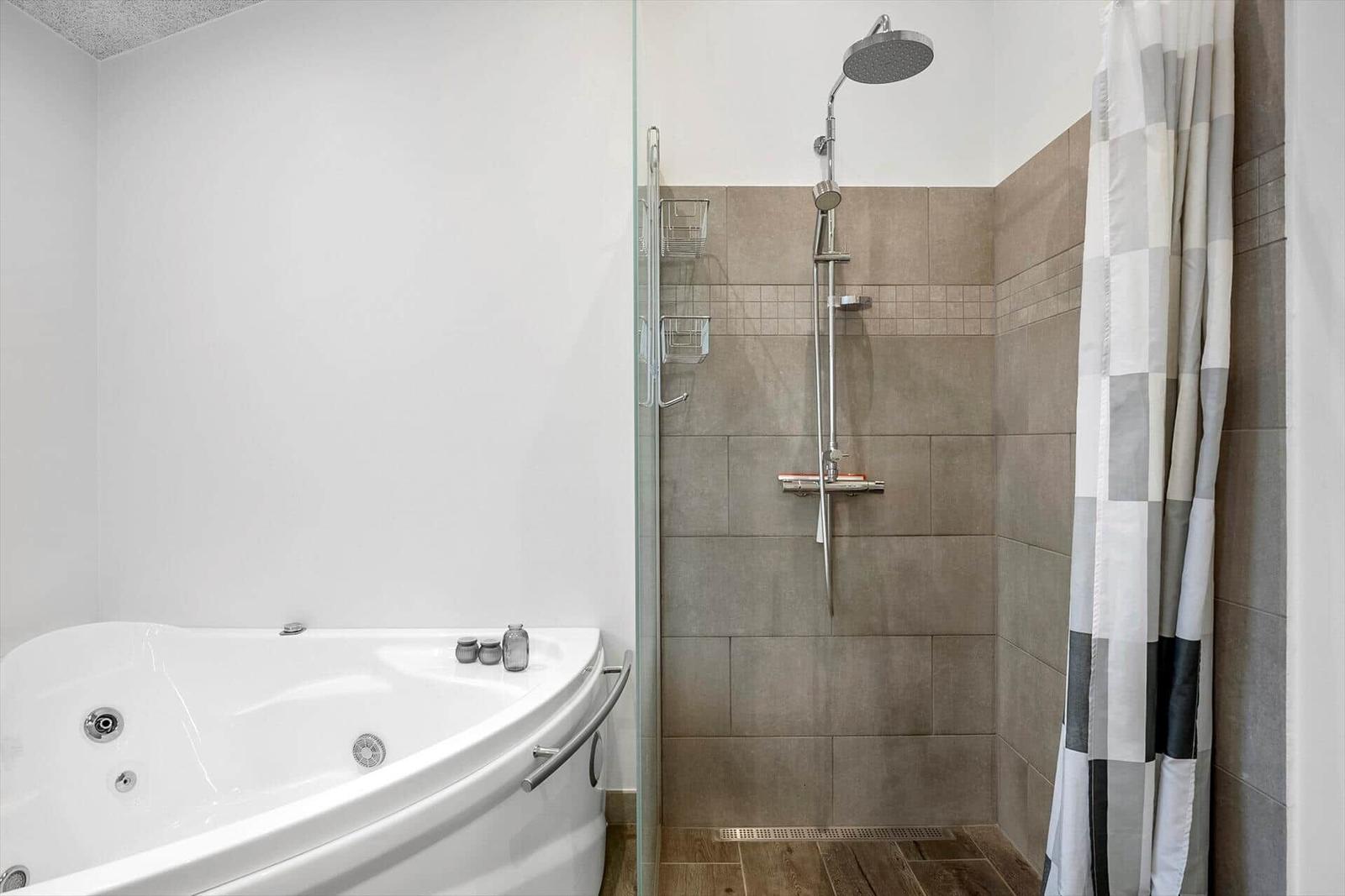 Bath with whirlpool tub and shower with shower curtain.