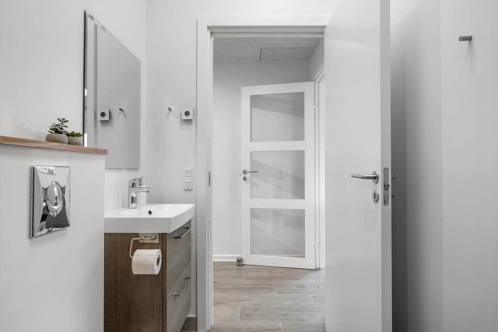 Bathroom with sink, mirror, and door to hallway.