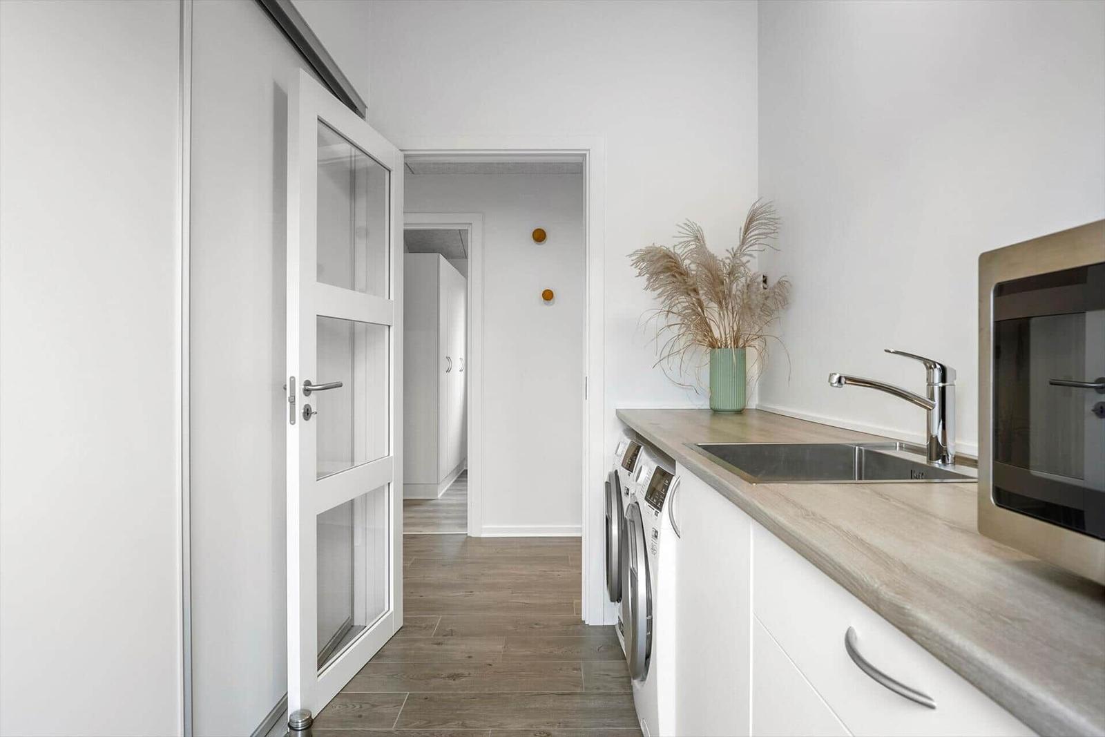 Kitchen with sink, microwave, and washing machine. Door leads to hallway.