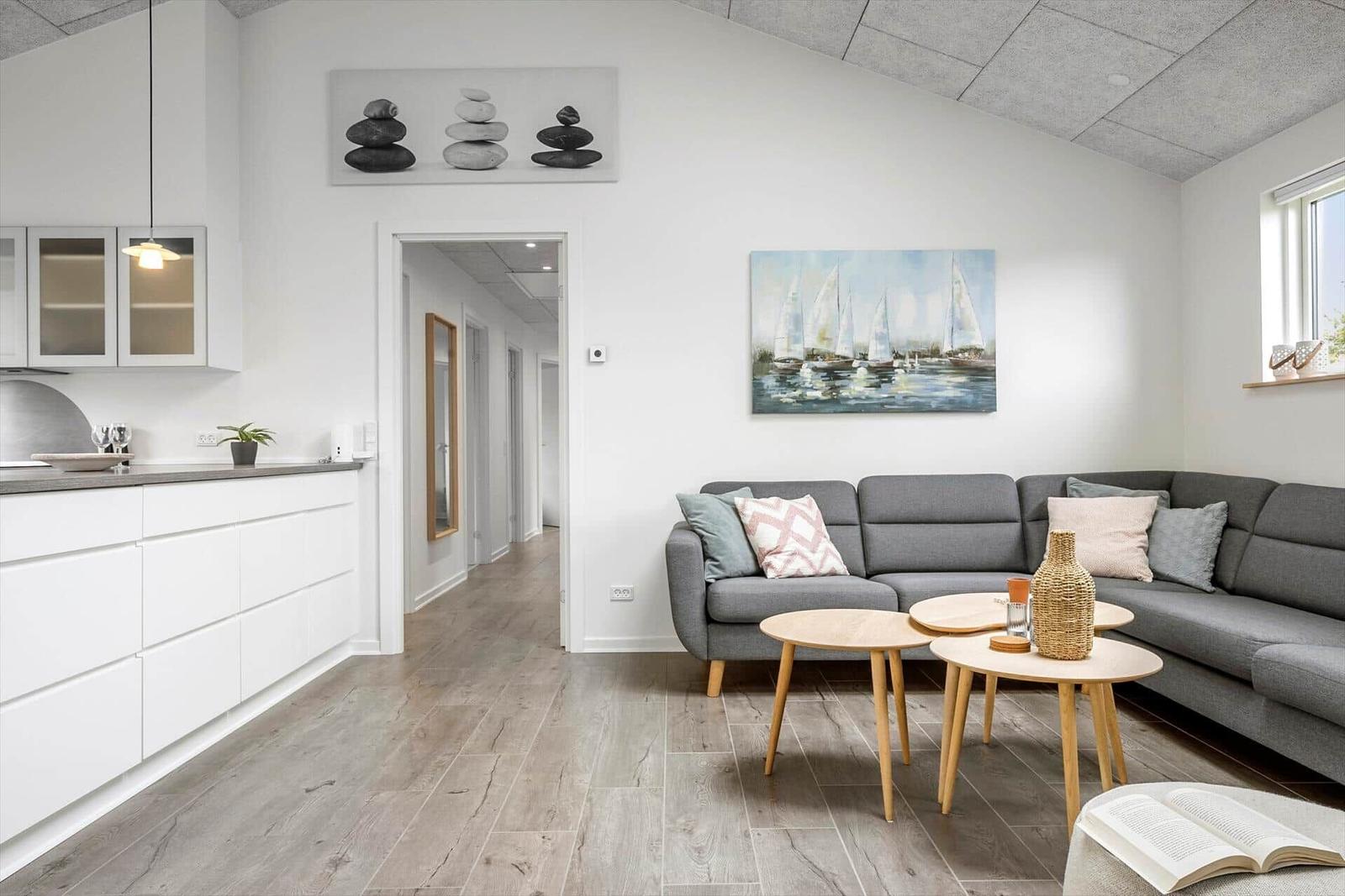Living area with gray sofa, two round tables, and kitchen area.