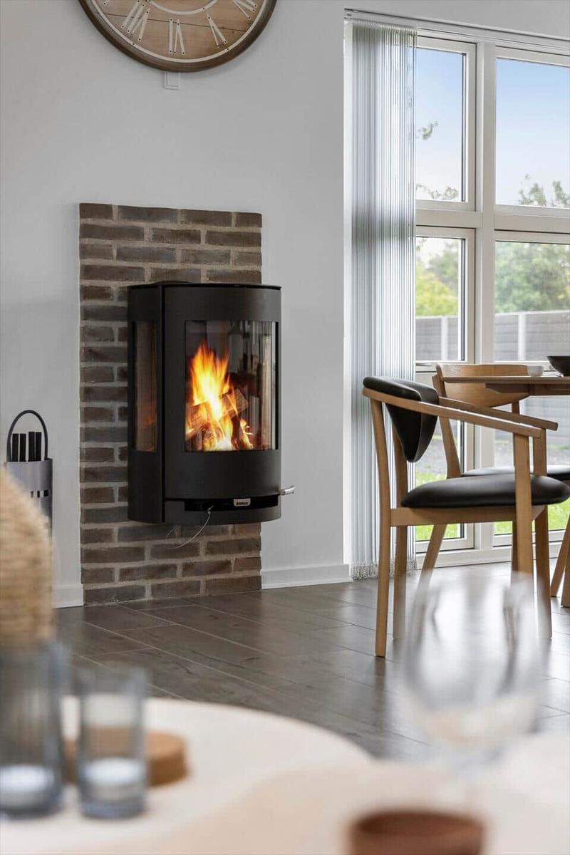 Living room with fireplace, table and chairs. Window with view outside.