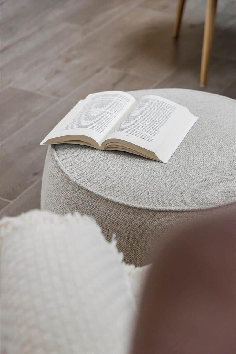 A book rests on a round cushion on the floor.