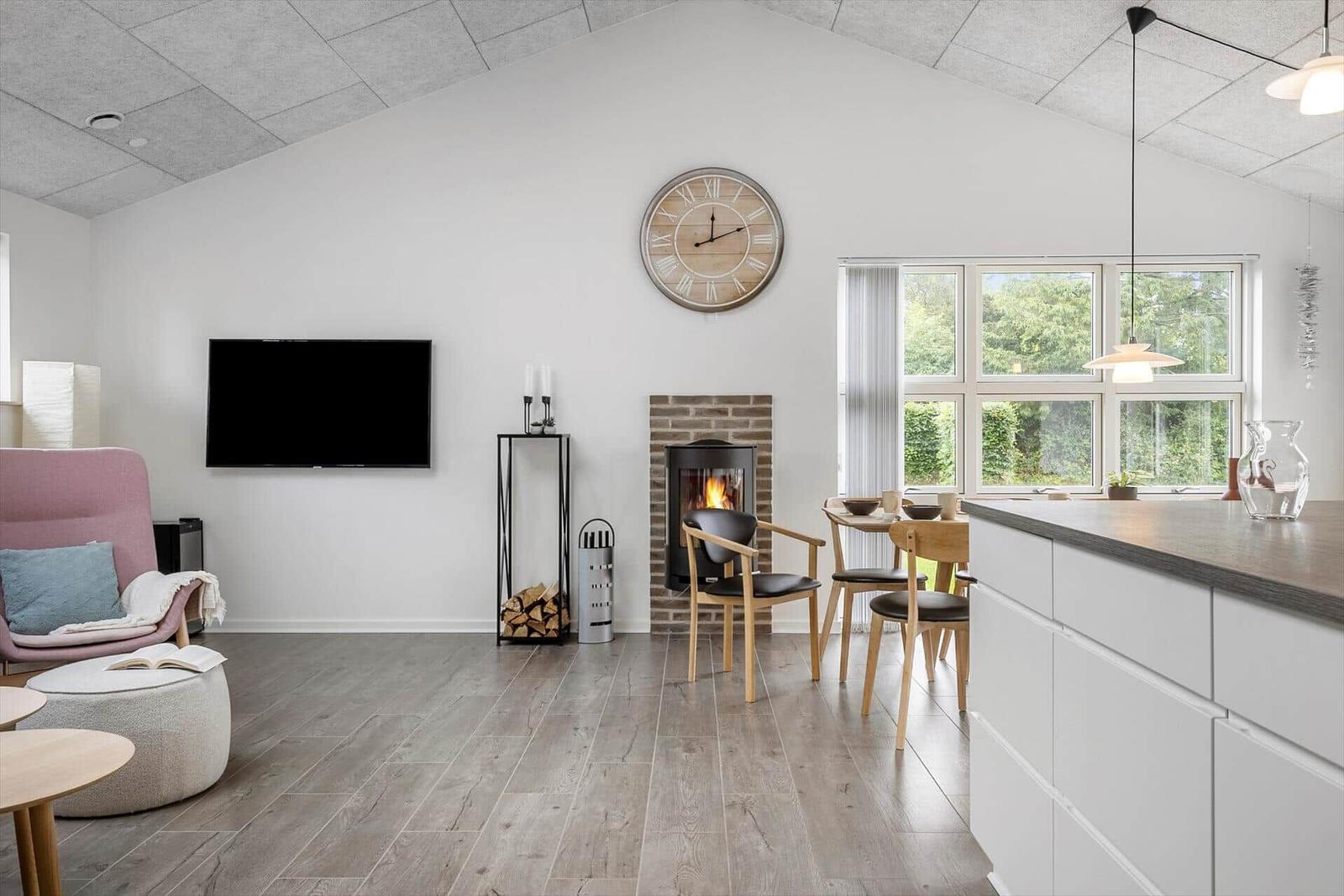 Living and dining area with fireplace, TV, and large window.