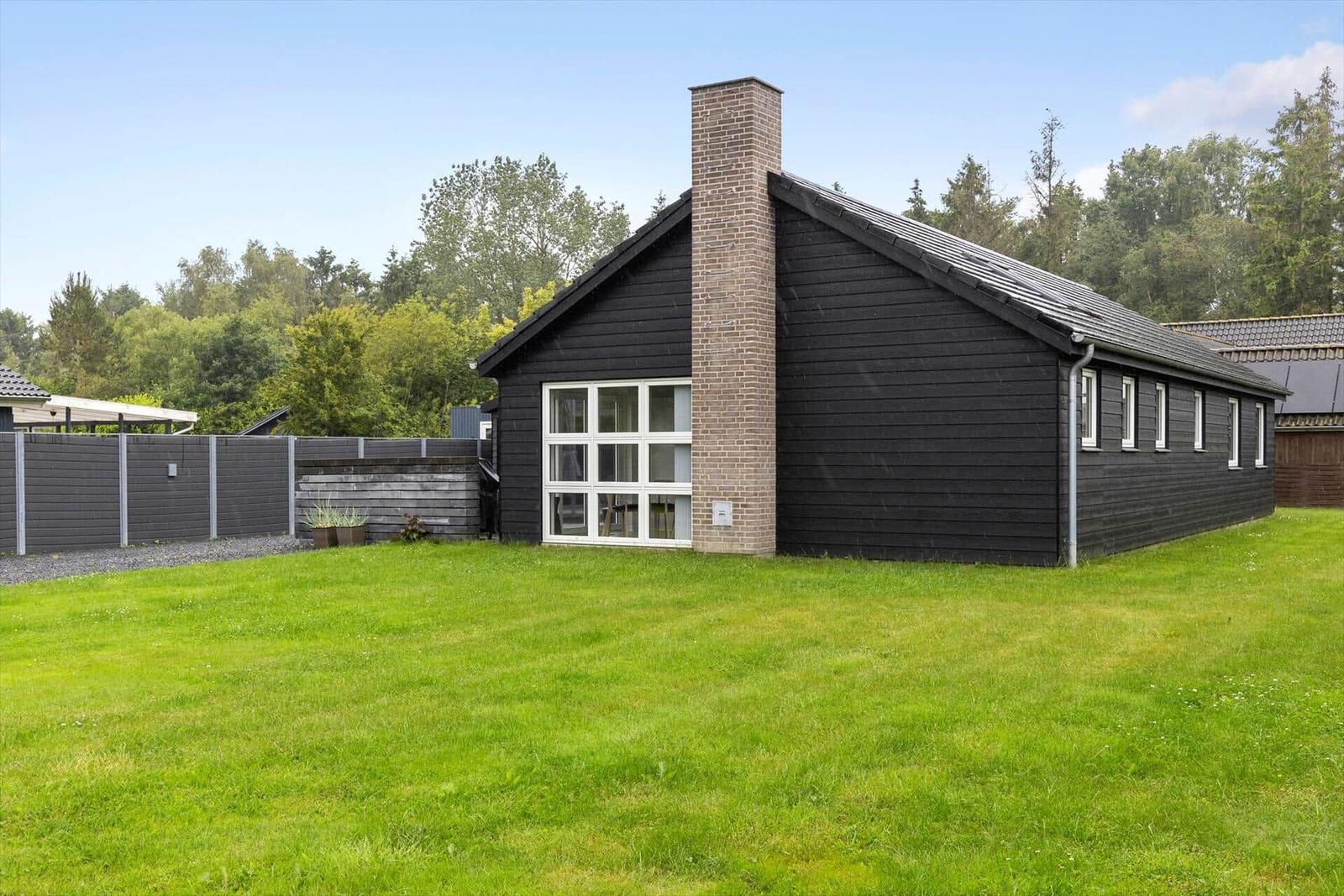 Black wooden house with chimney and large garden