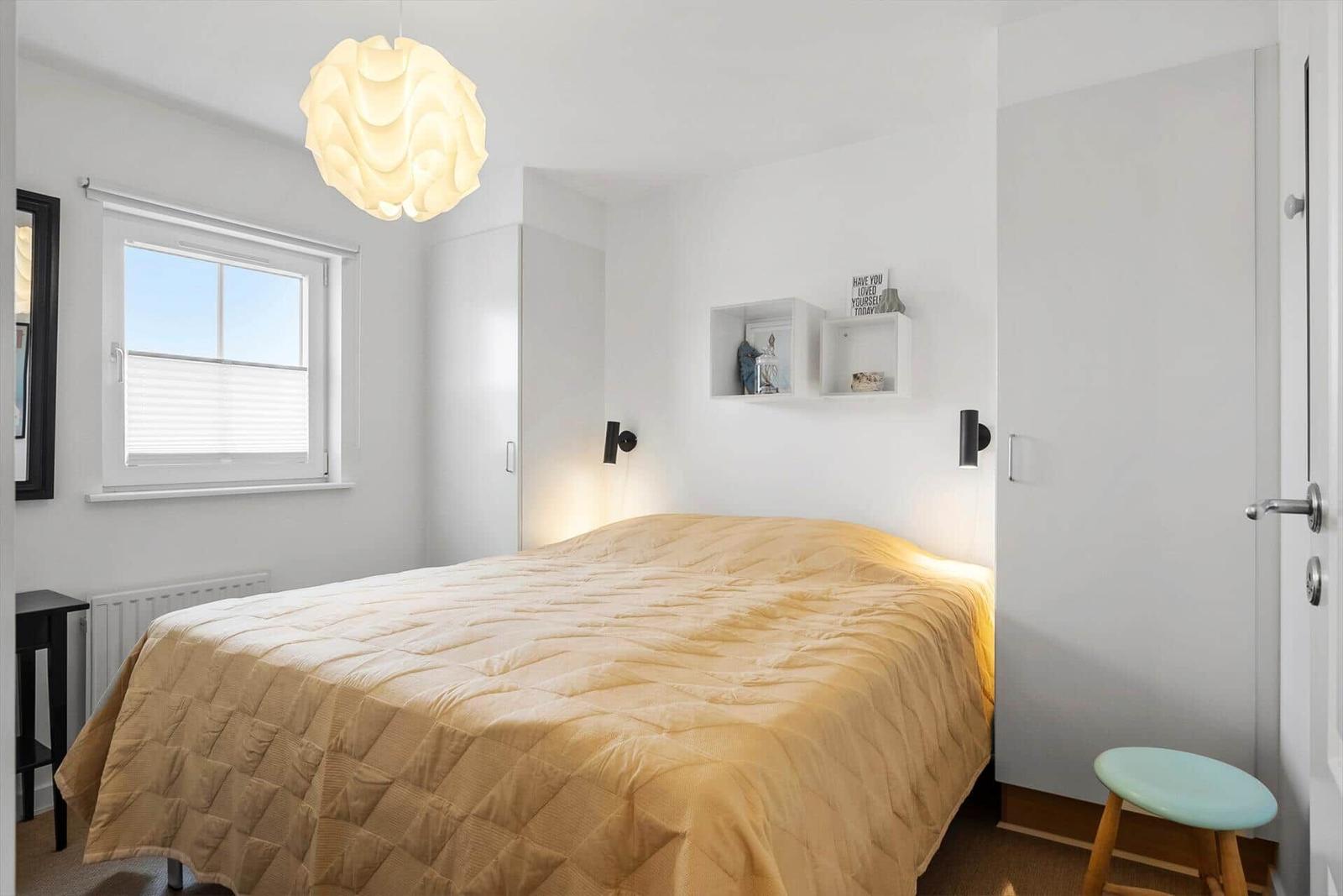 Schlafzimmer mit Bett, Fenster und Deckenleuchte.