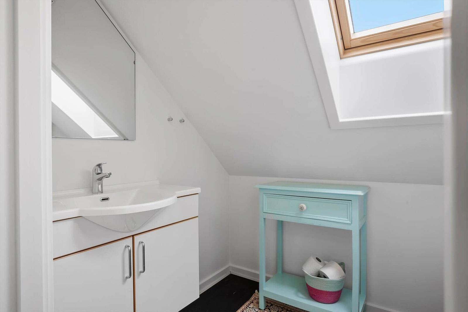 Badezimmer mit Waschbecken, Spiegel und Dachfenster.
